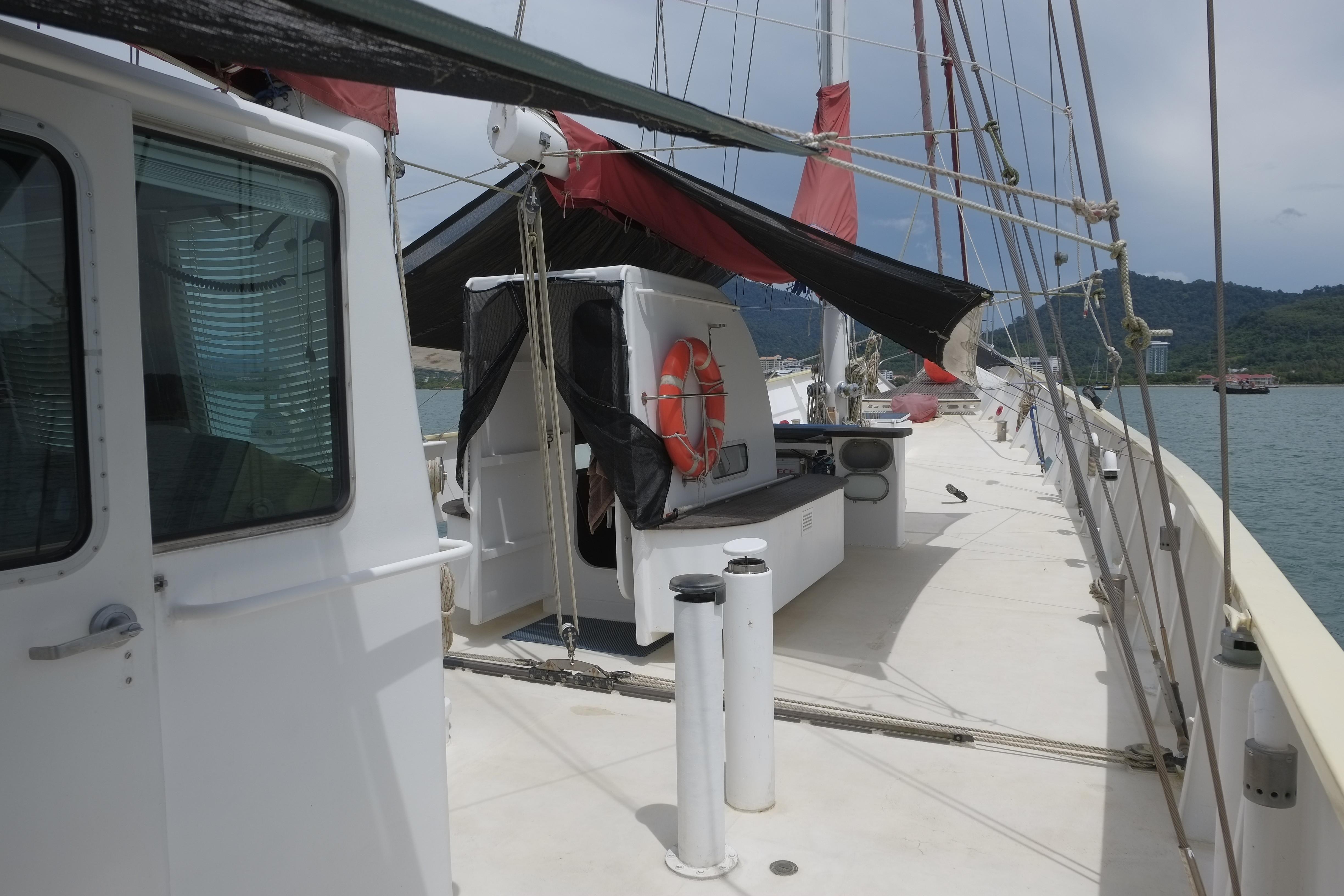 Custom 1986 schooner deck with lifebuoy, sails, and scenic water view.