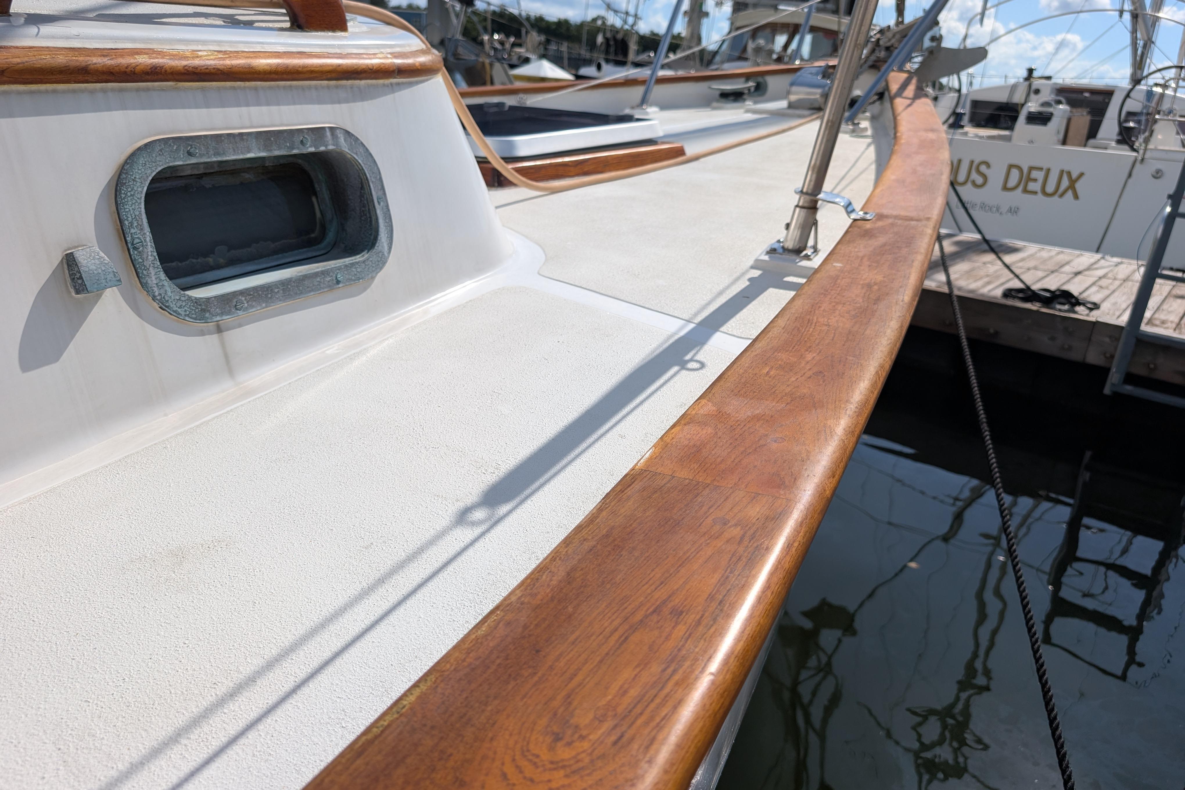 1983 Robert Perry 41 sailboat deck with wooden trim and porthole, docked at marina.