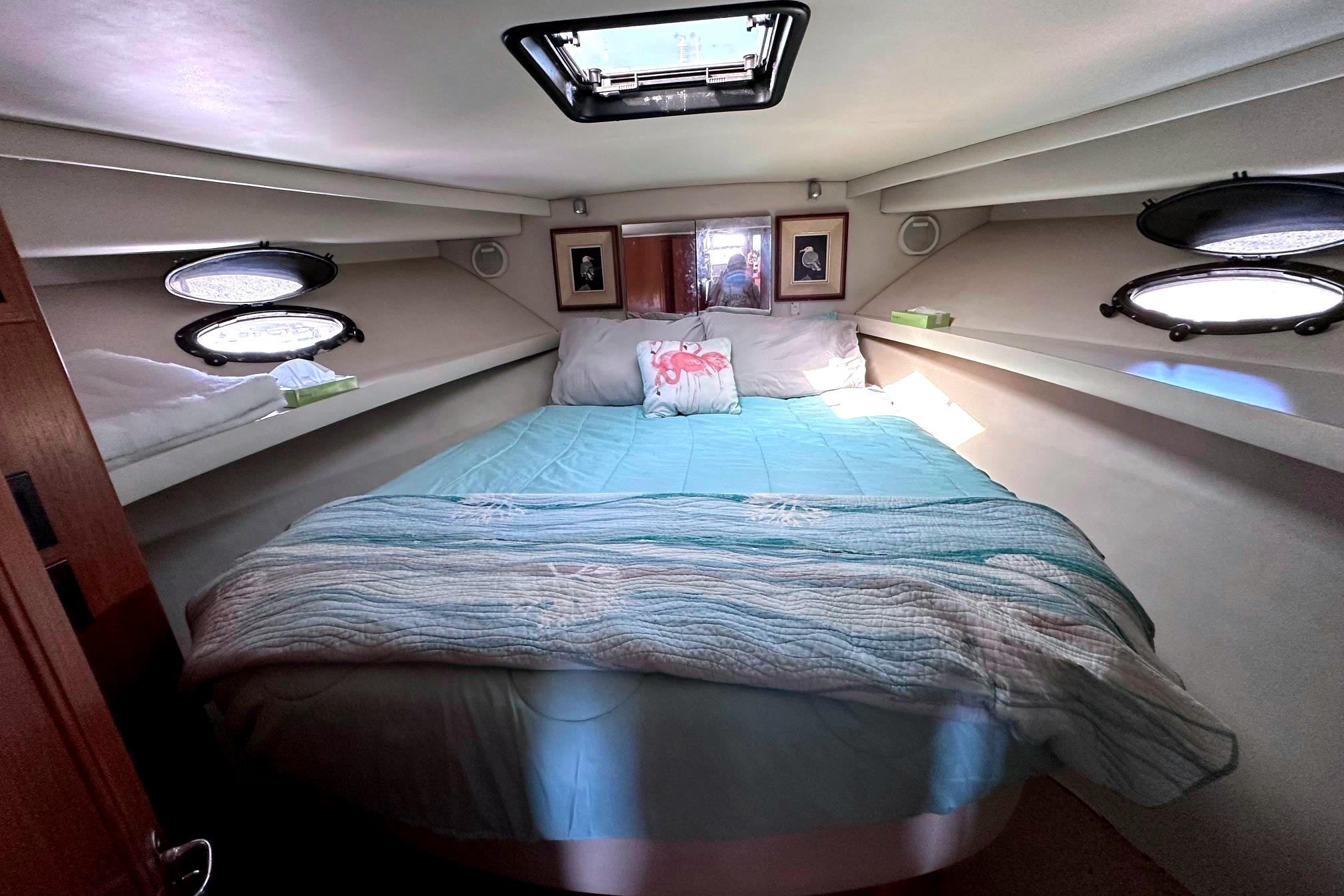 Cozy bedroom in 1991 Californian 52 Cockpit Motor Yacht with skylight and portholes.