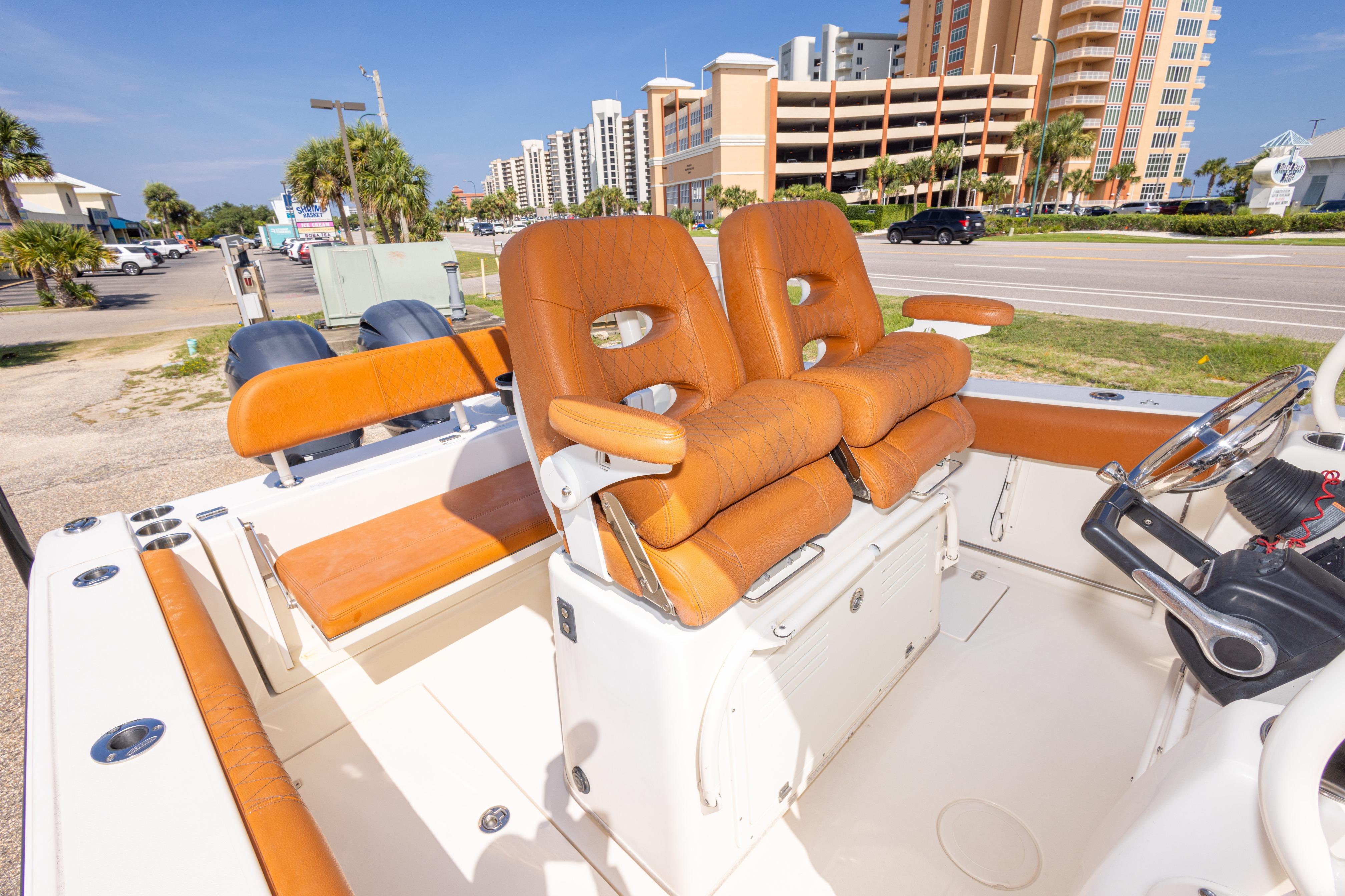 2017 Cobia 261 Center Console boat with tan seating, parked near a coastal road.