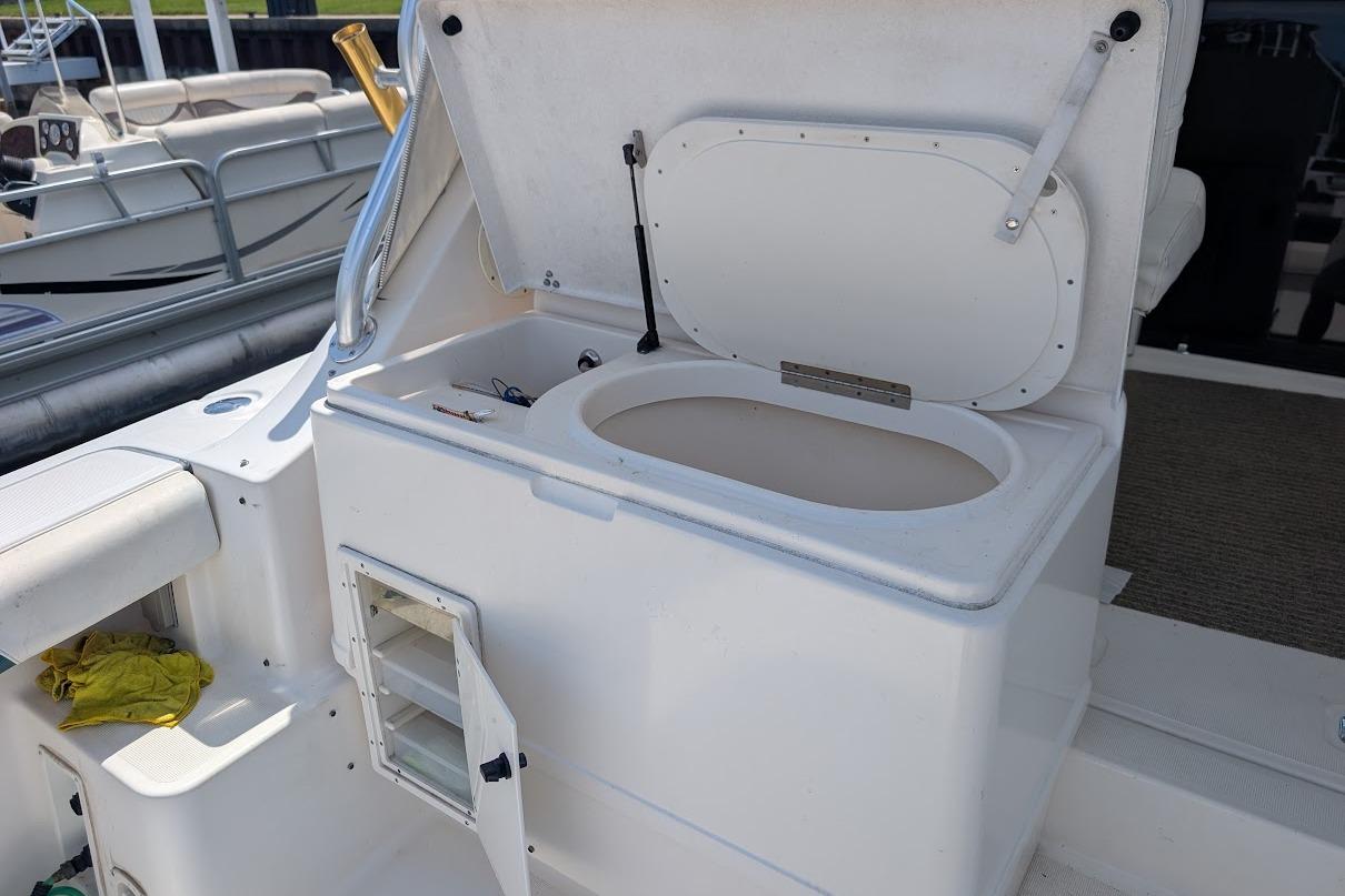 Open storage compartment on a 2000 Pursuit 3400 Express boat, docked at a marina.