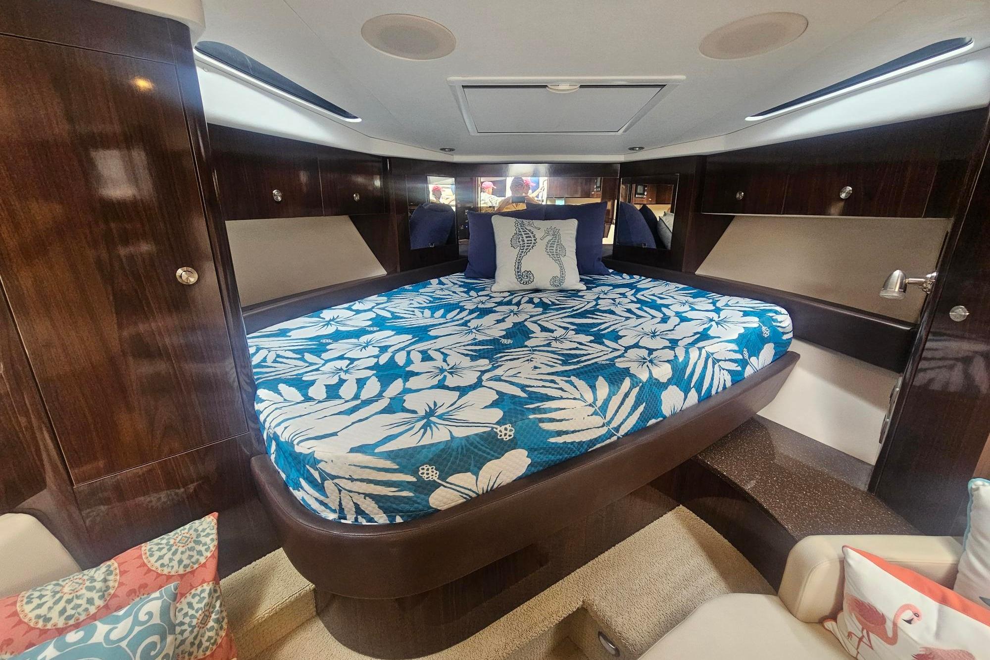 Luxurious cabin interior of 2016 Sea Ray Sundancer 350 with floral bedding and elegant wood finishes.