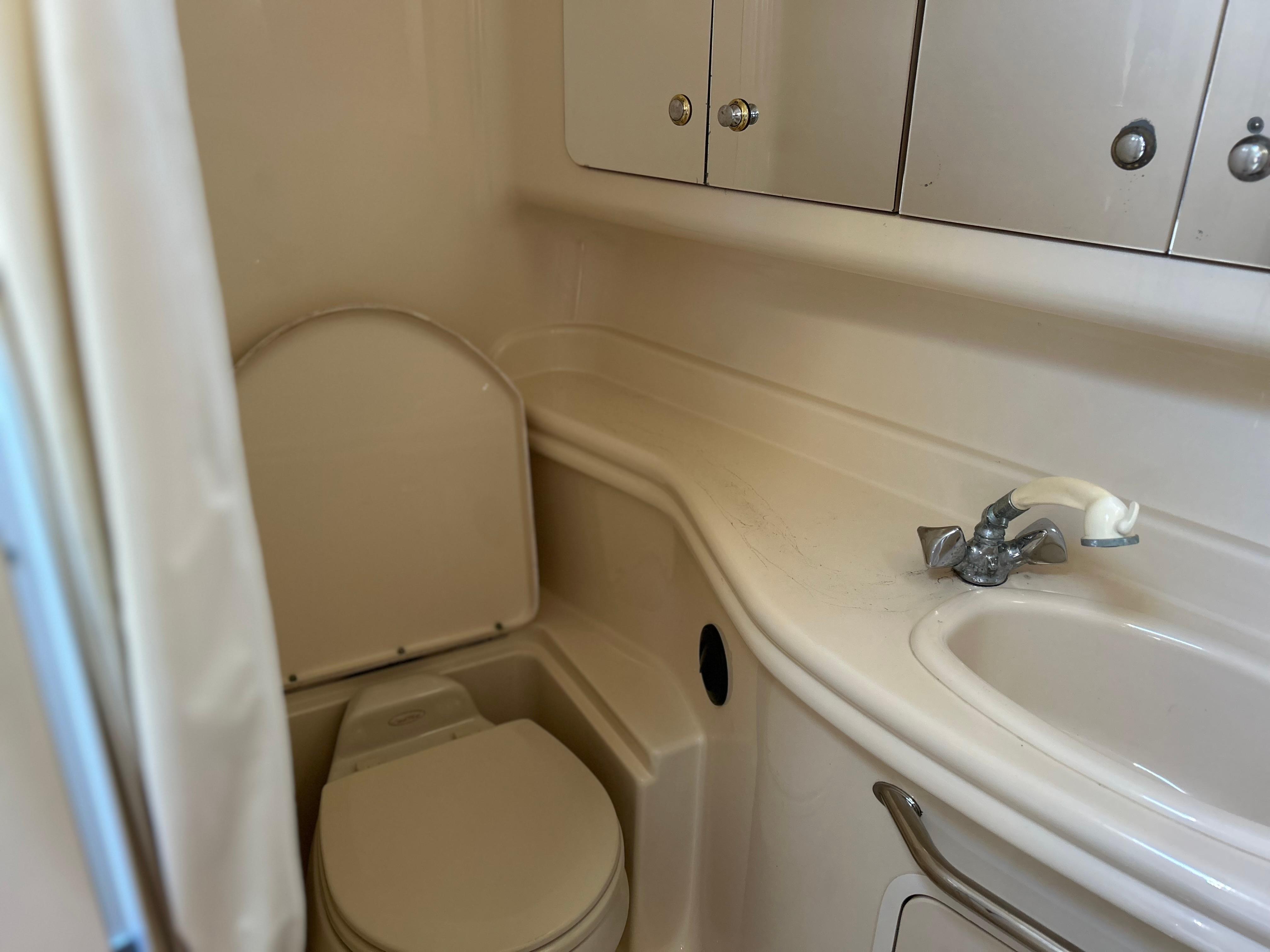 2004 Sea Ray 340 Sundancer bathroom with toilet, sink, and storage cabinets.