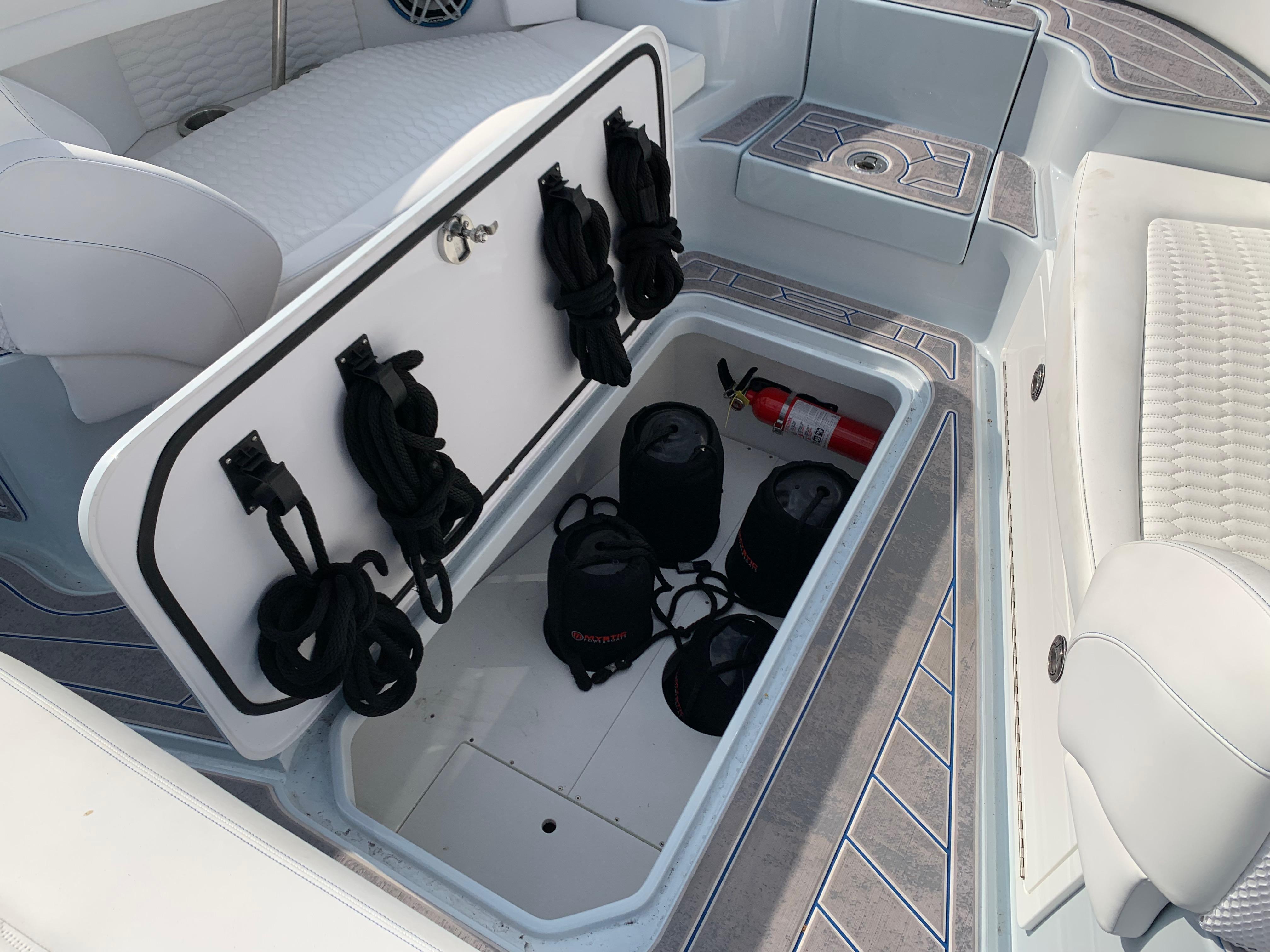 Storage compartment in 2023 Mystic Powerboats M3800, featuring ropes and a fire extinguisher.