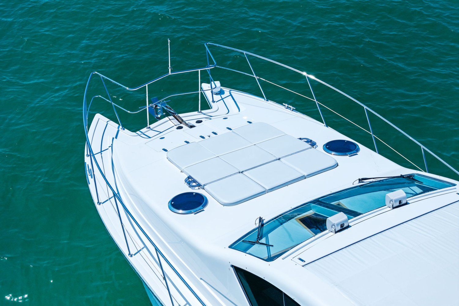 A sleek catamaran with a white deck and blue railings on calm water.