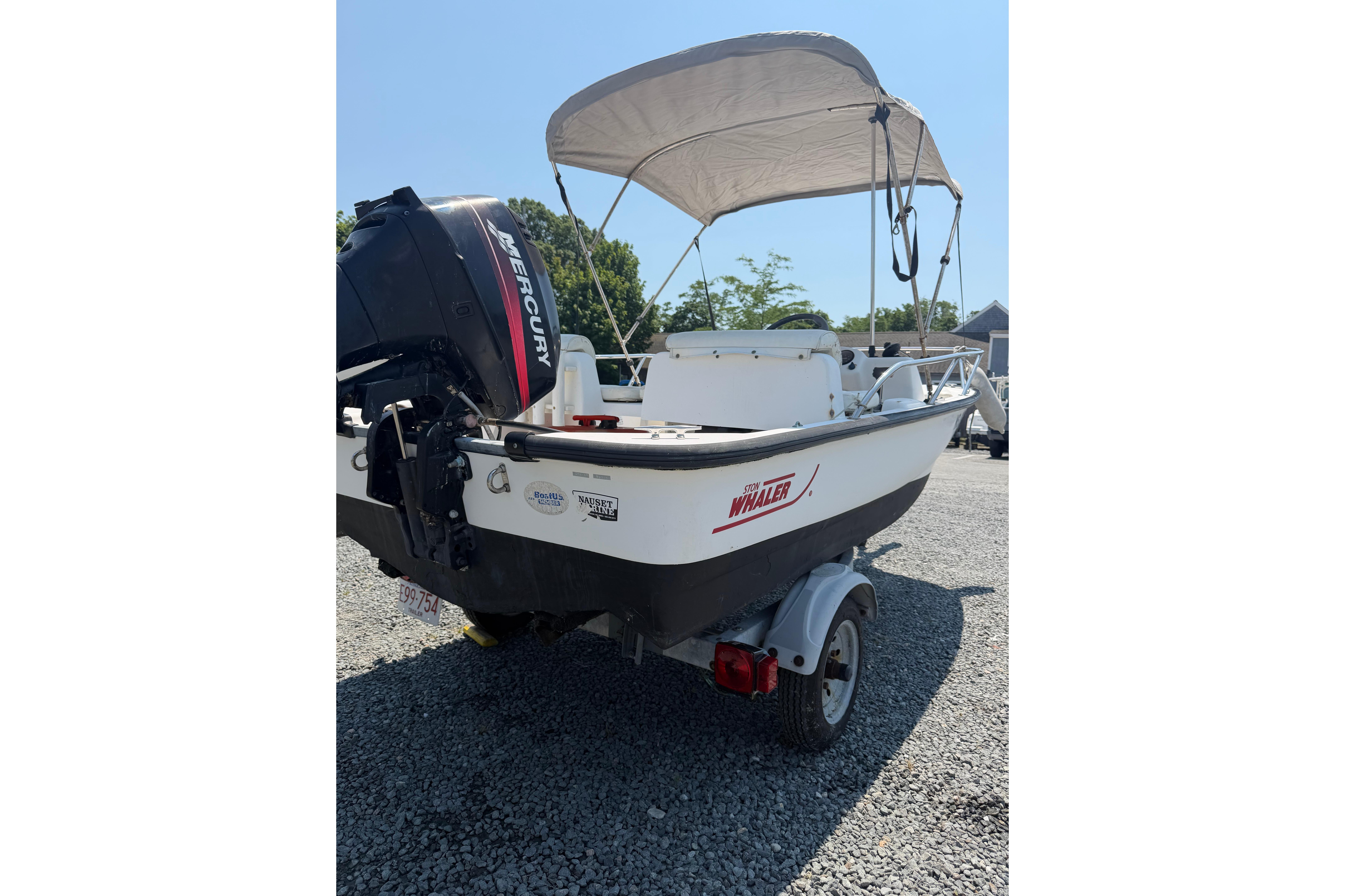 2003 Boston Whaler 130 Super Sport boat with Mercury engine and canopy on trailer.