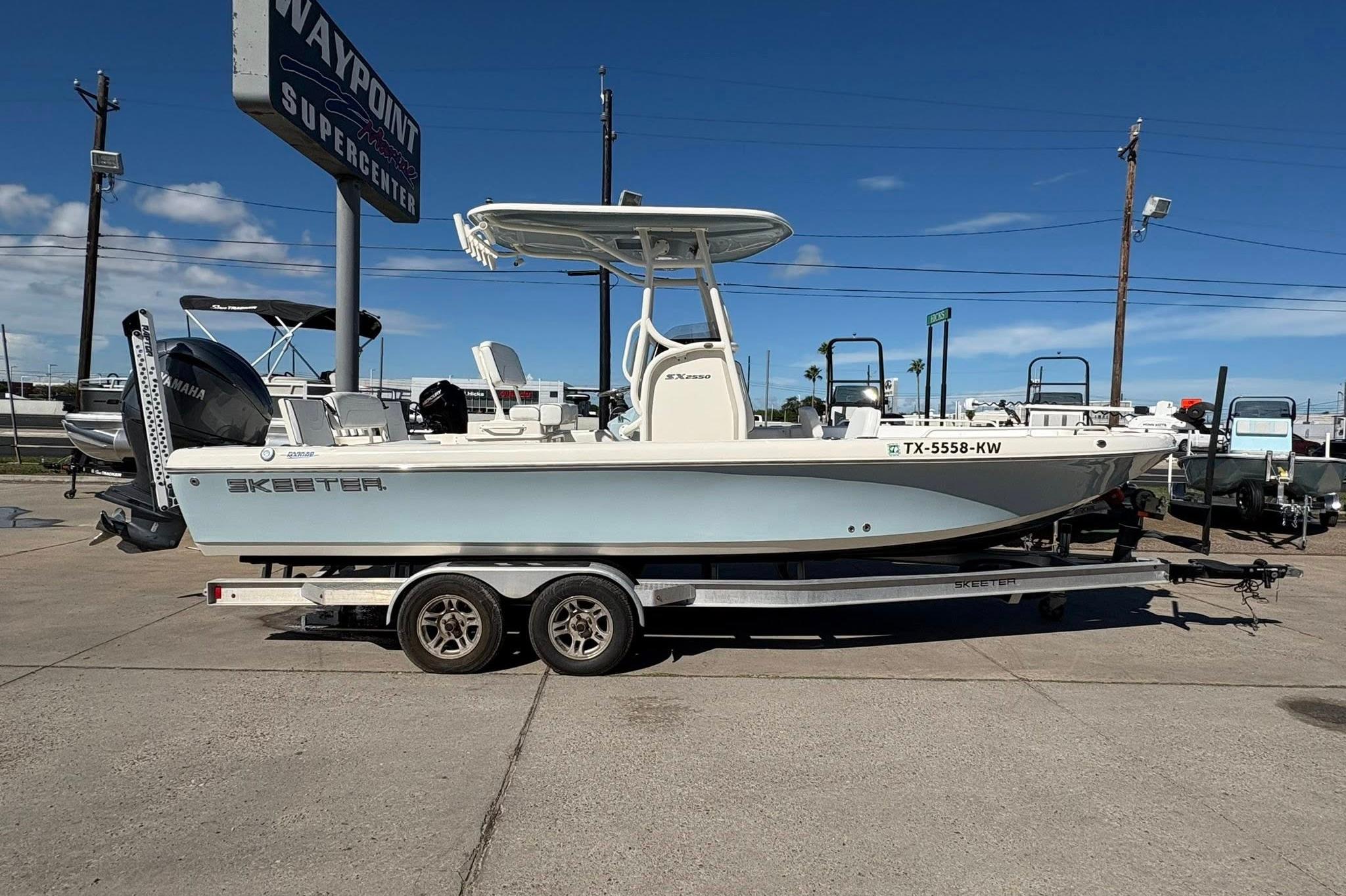 2023 Skeeter SX2550 Family boat on trailer at dealership under clear blue sky.