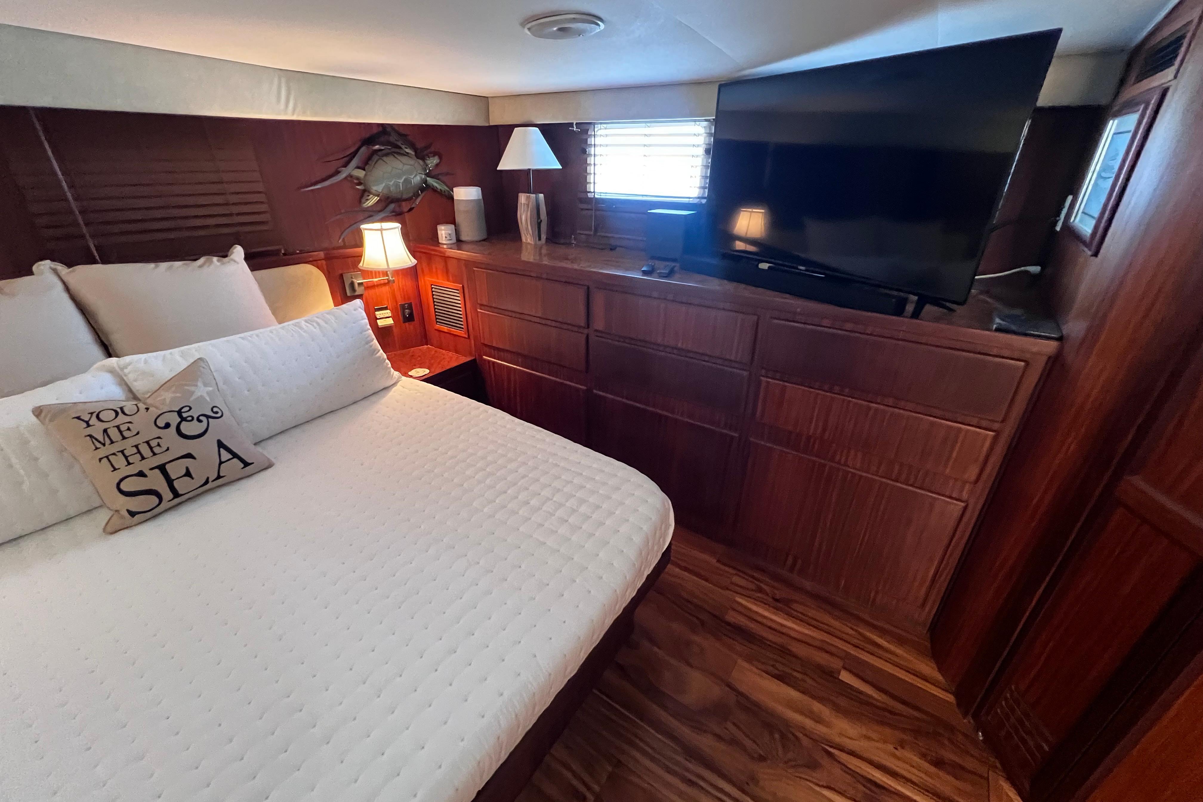Luxurious bedroom interior of 1987 Hatteras 70 Cockpit Motor Yacht with TV and cozy decor.