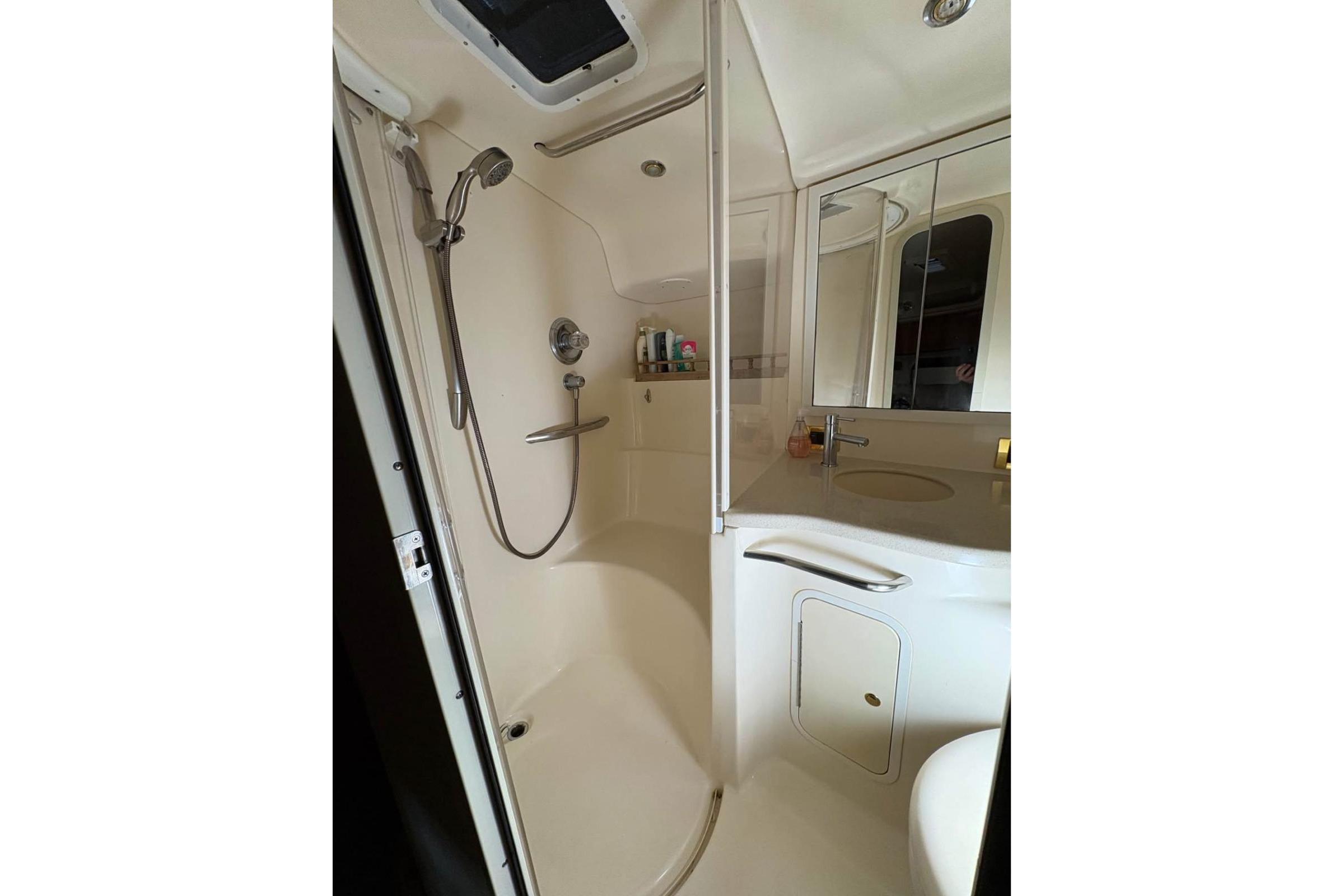 1999 Sea Ray 400 Sundancer bathroom with shower, sink, and mirrored cabinet.