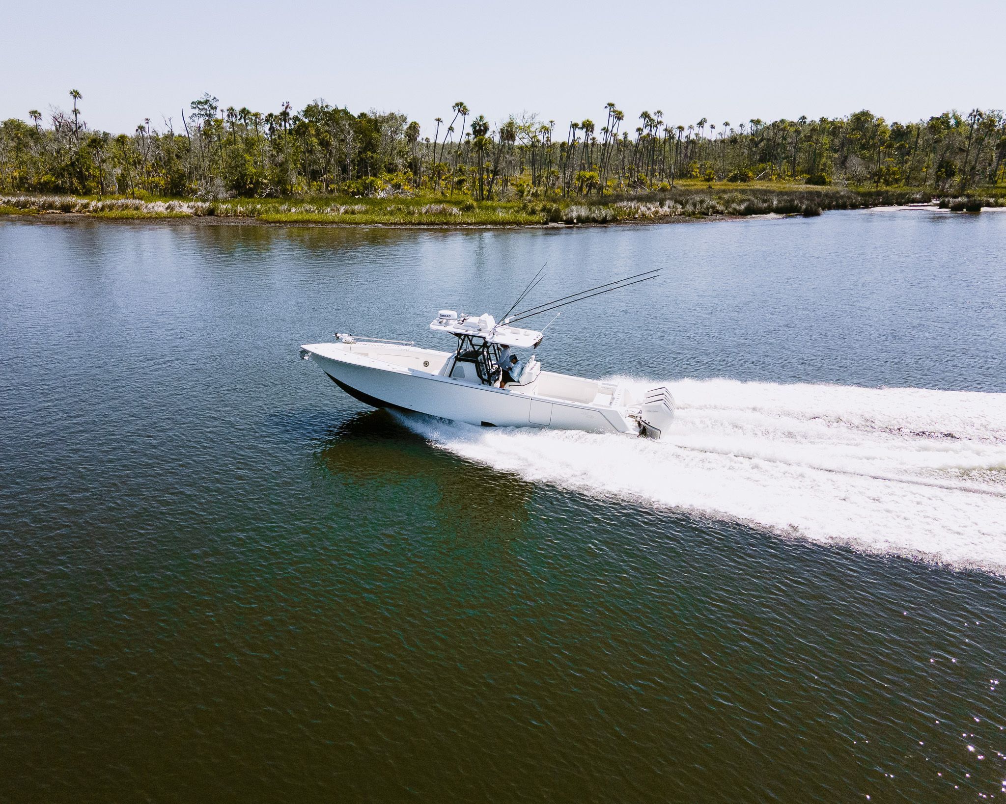 A 2022 SeaVee 370Z speeds across calm water, surrounded by trees along the shoreline.
