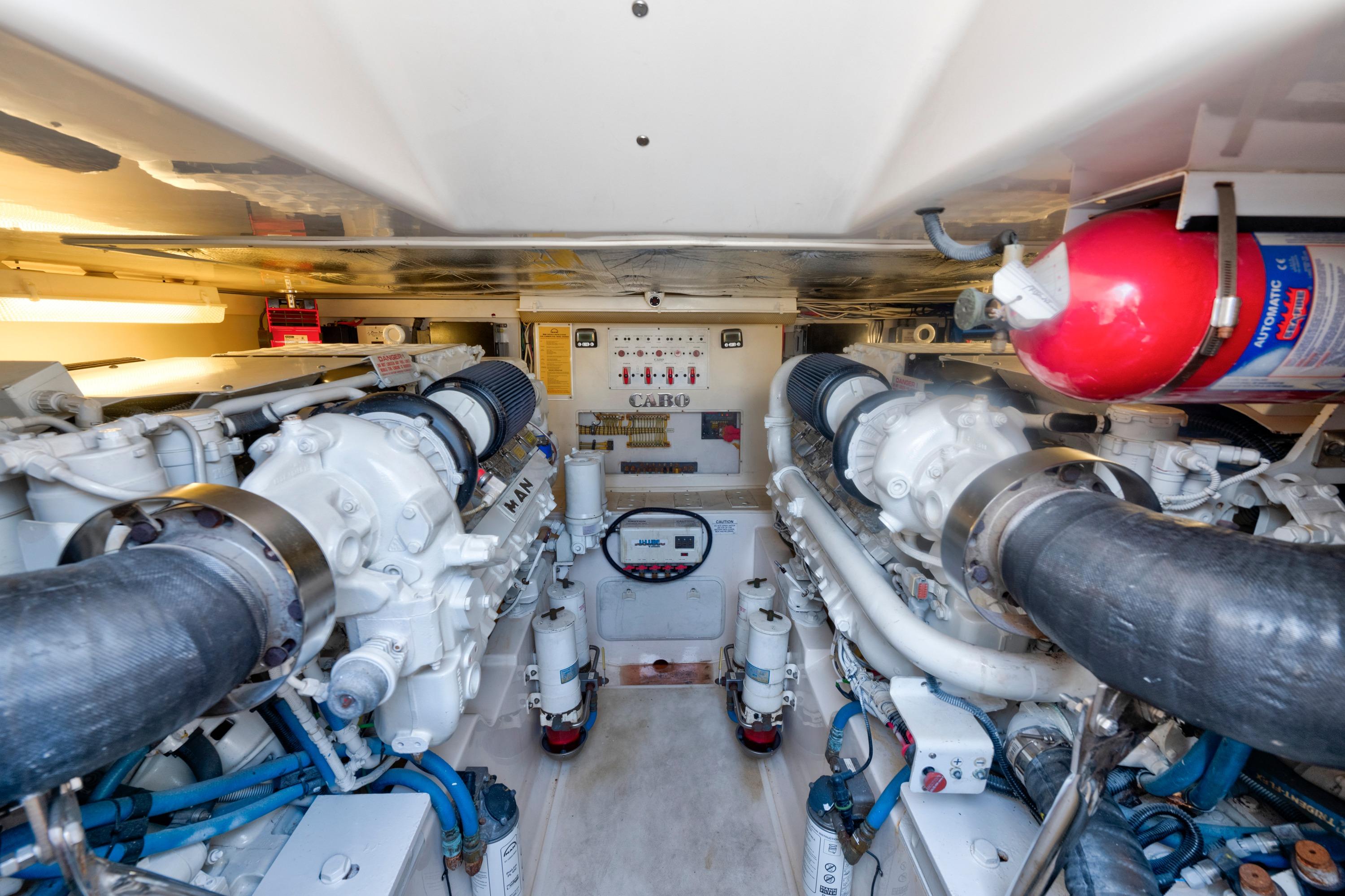 Engine room of 2010 Cabo 45 Express yacht with dual engines and fire extinguisher.