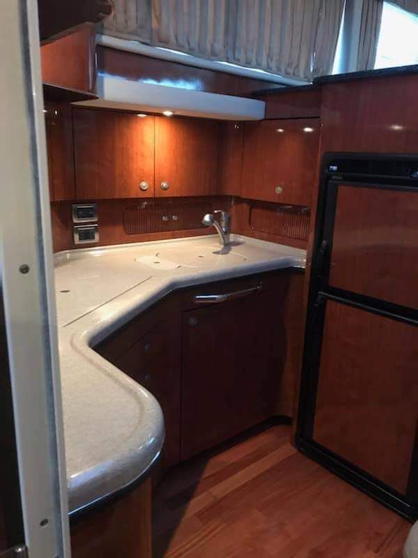 Kitchen with wooden cabinets and countertop in a 2004 Sea Ray Sedan Bridge.