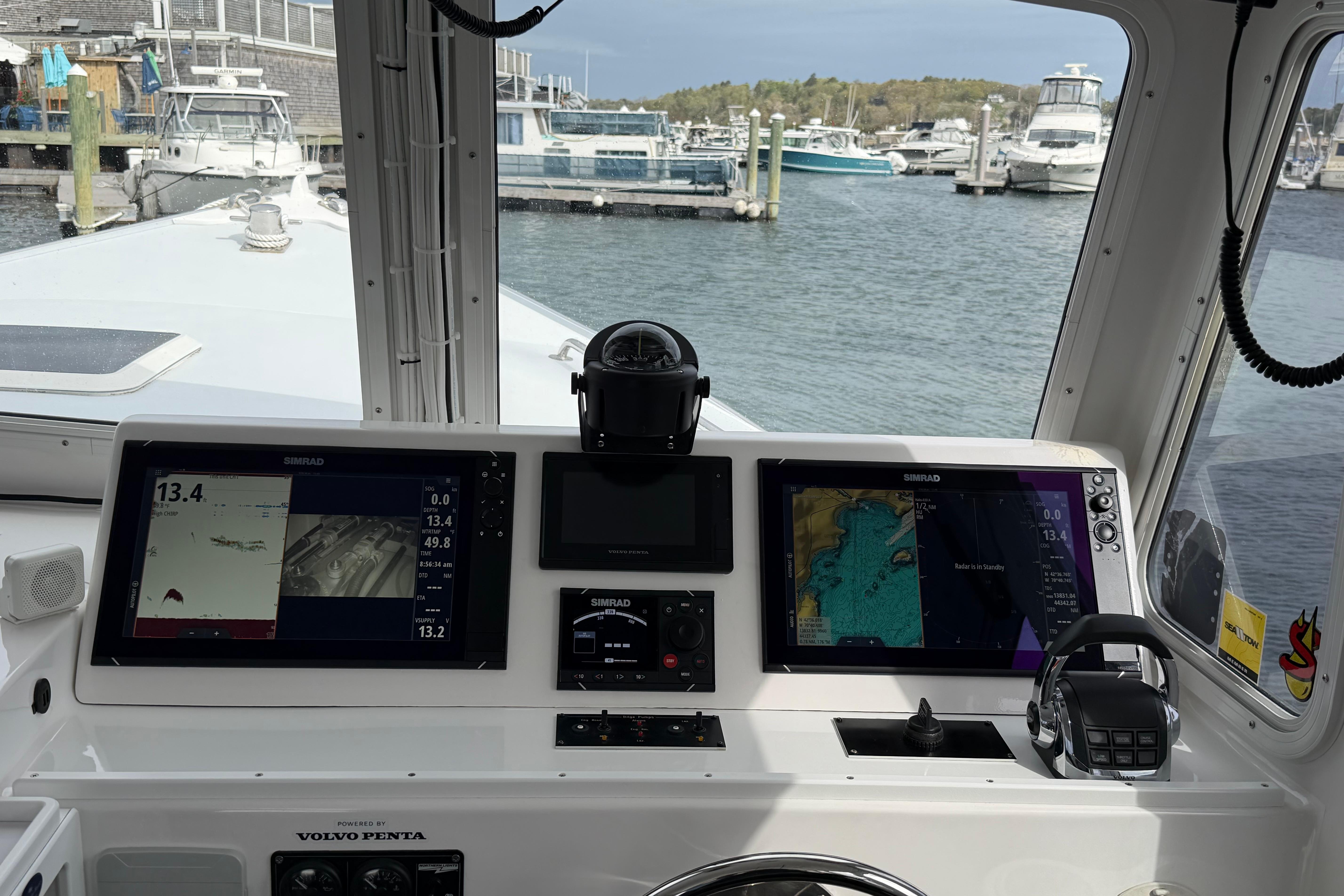 Helm of 2018 H&H Marine Osmond Beal boat with navigation screens in a marina.