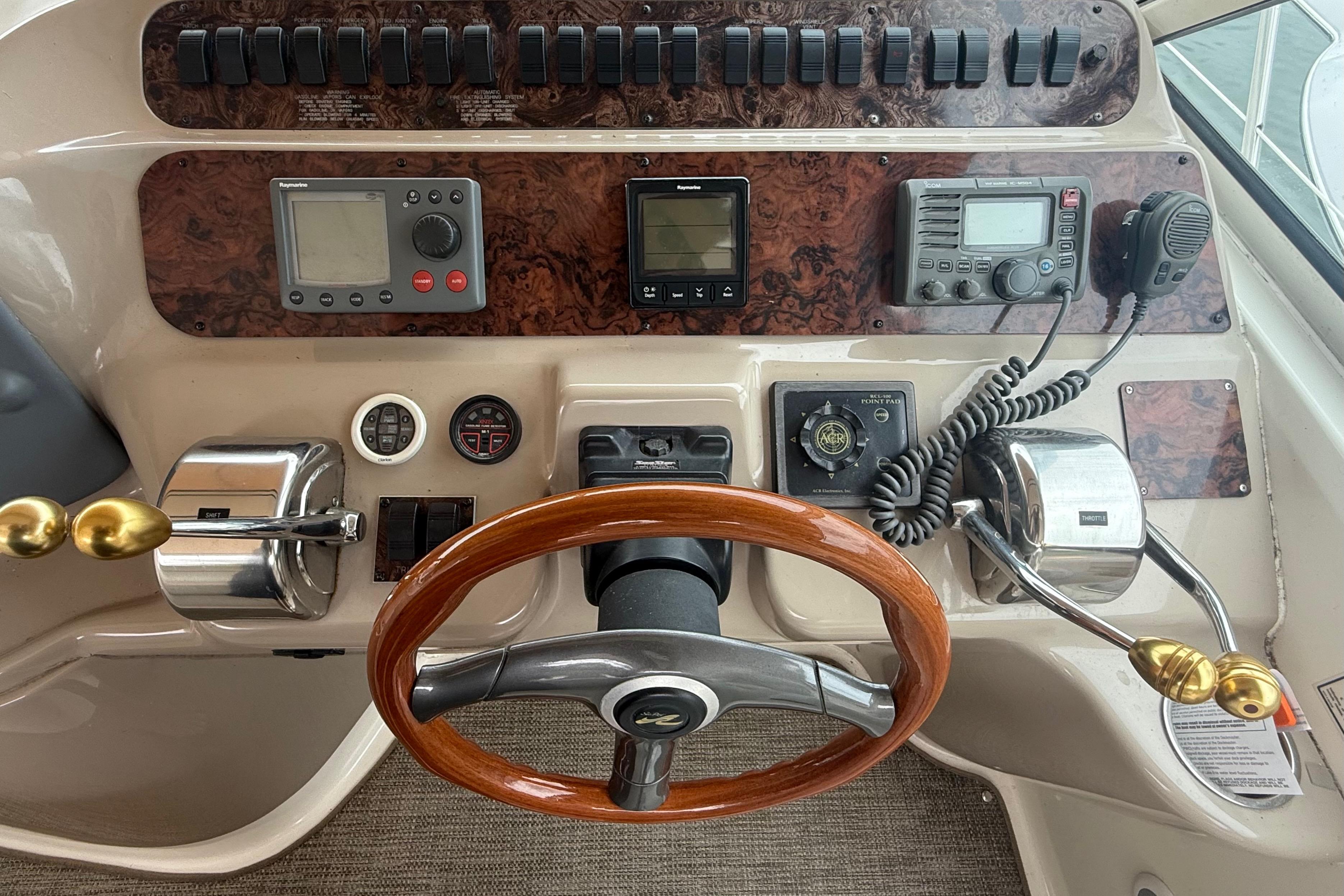 1998 Sea Ray Sundancer 400 helm with wood steering wheel and navigation controls.