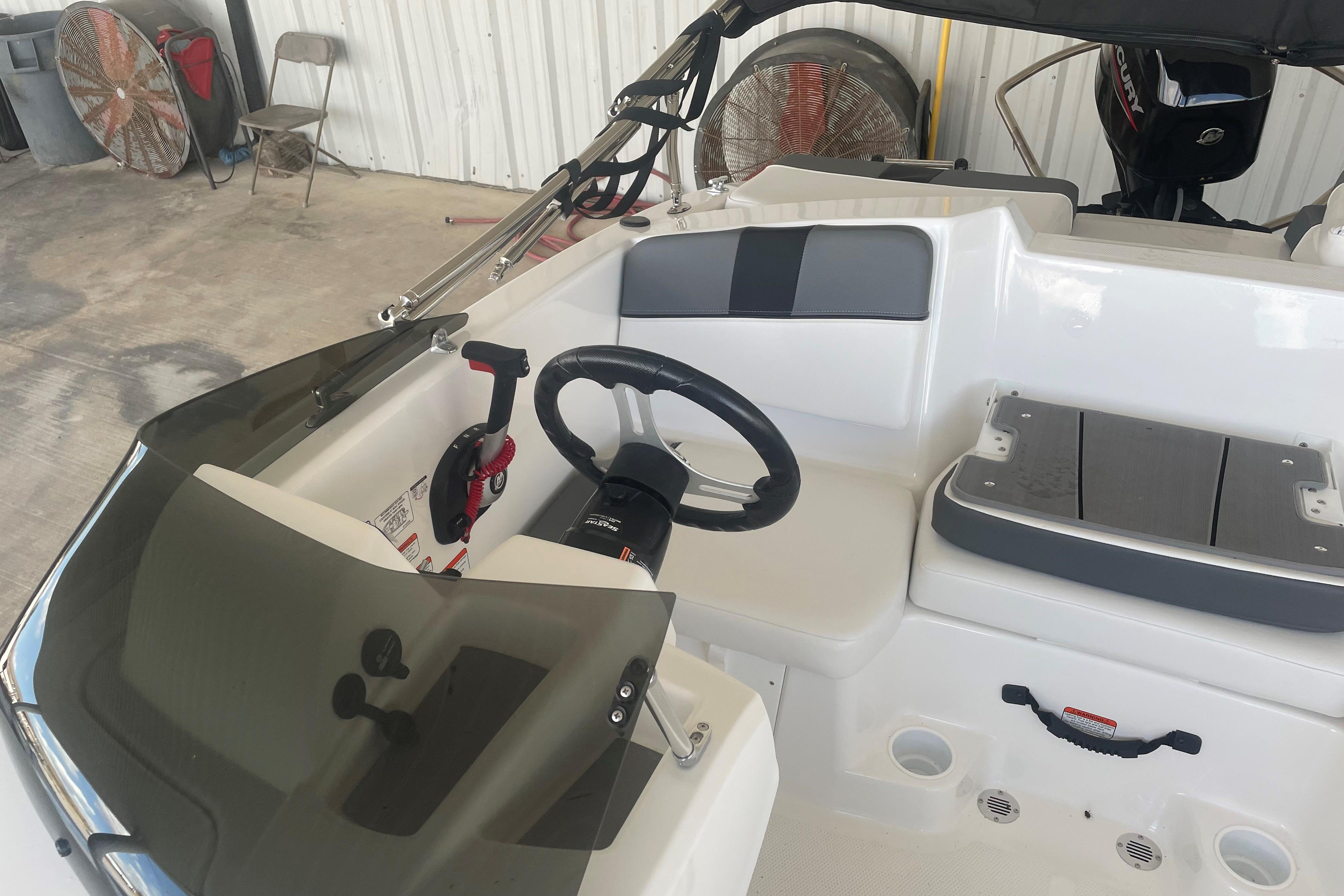 2026 Tahoe T16 boat interior with steering wheel and seating in a garage setting.