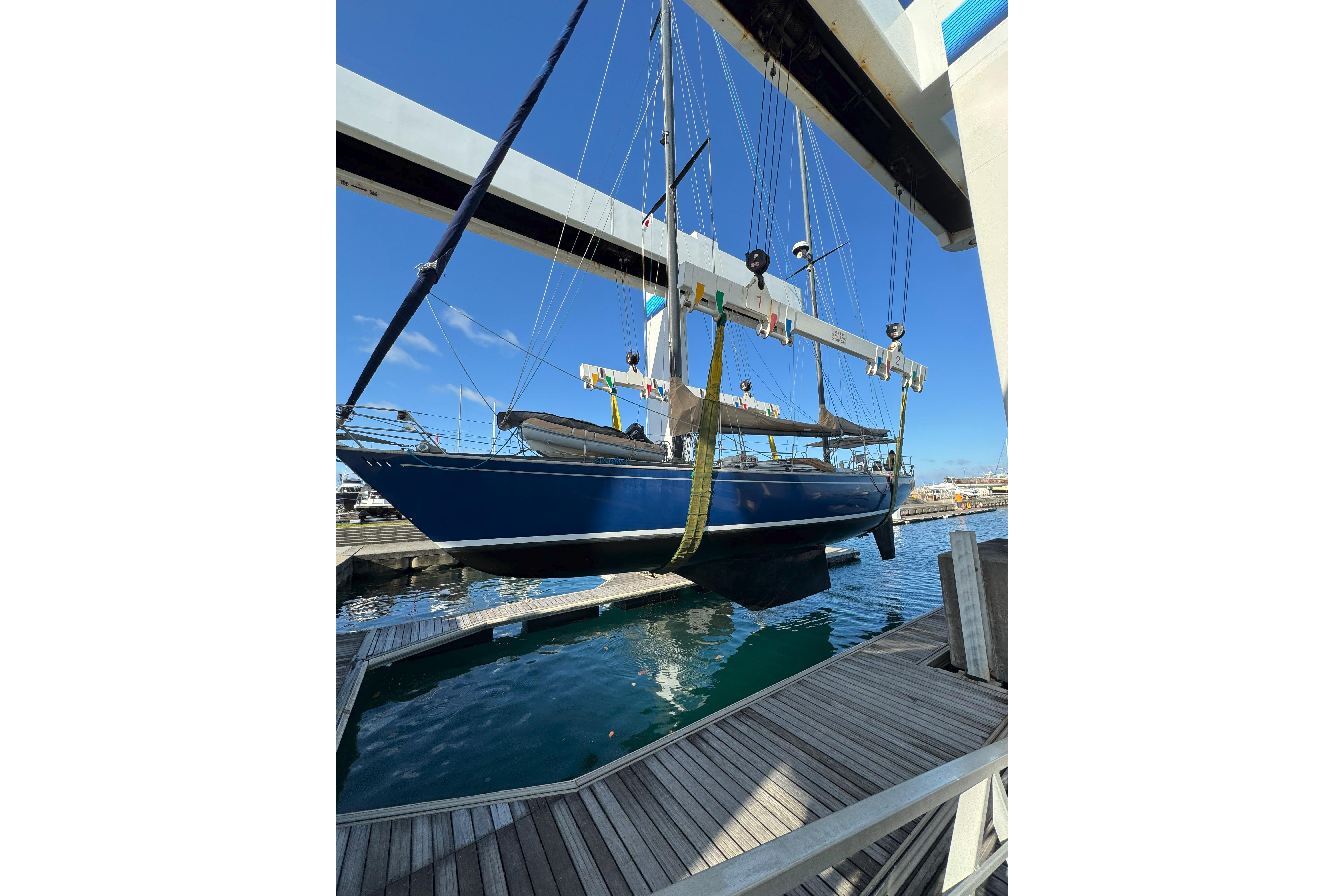 A 1983 SKYE 51 sailboat being lifted at a marina, showcasing its sleek blue hull.