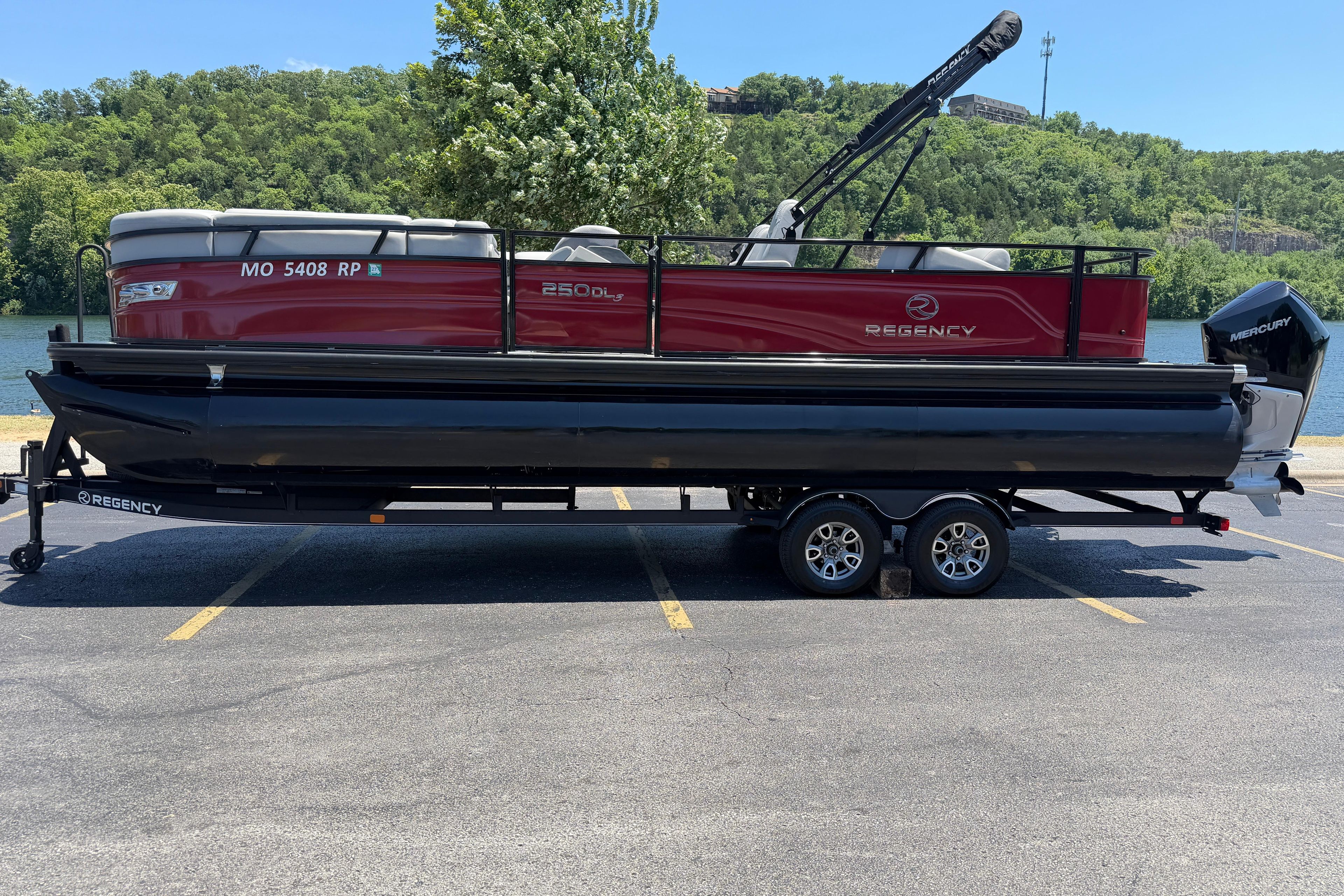 2024 Regency R250DL3 pontoon boat on trailer, parked near a scenic lake.
