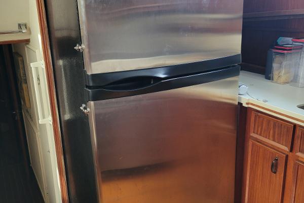 A stainless steel refrigerator in a yacht kitchen with wooden cabinets.
