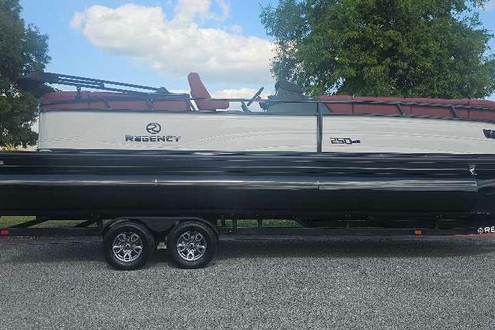 2026 Regency 250 DL pontoon boat on trailer, parked outdoors under a blue sky.
