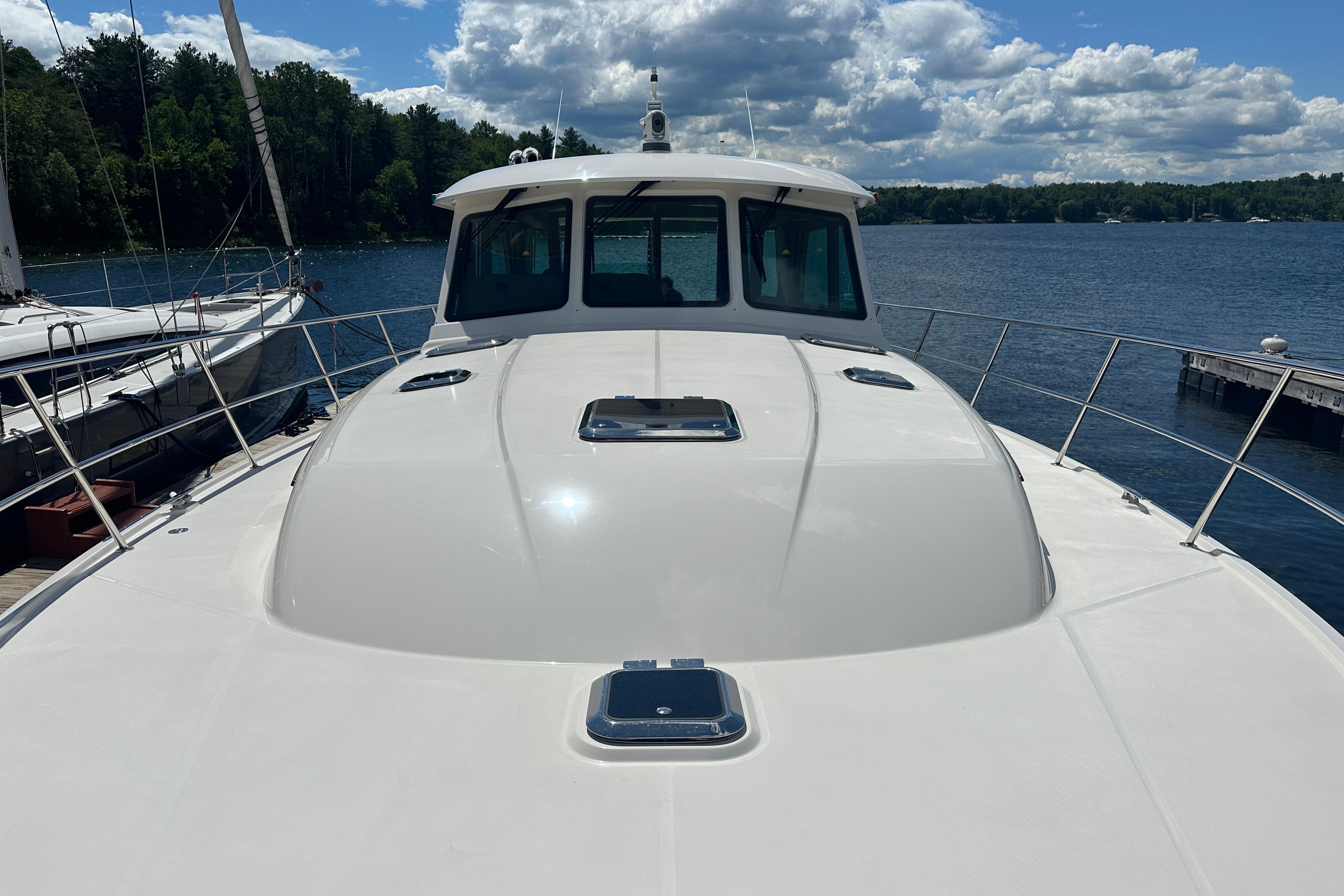 2025 Sabre 48 Salon Express yacht docked on a serene lake under a partly cloudy sky.