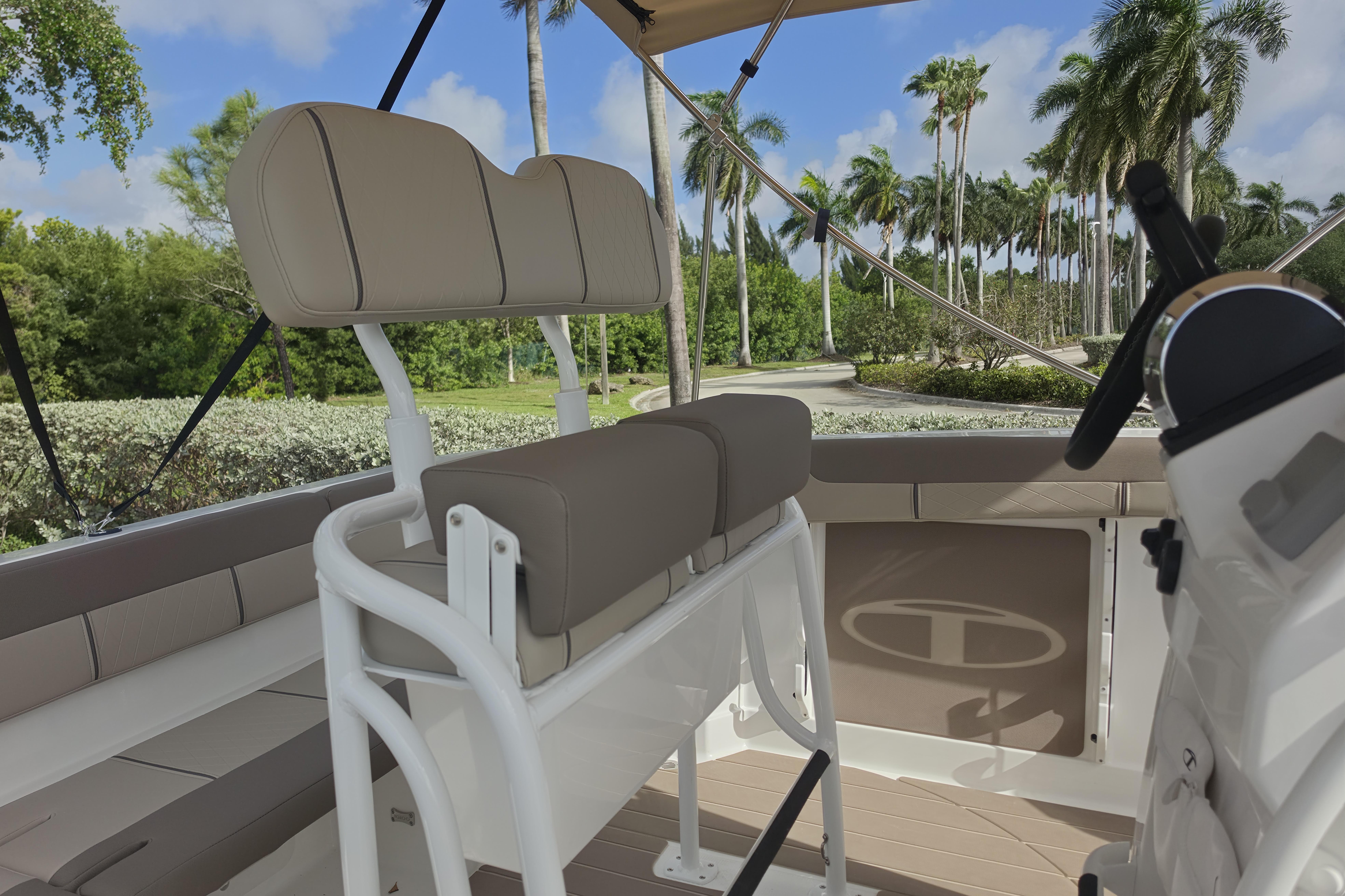 2026 Tahoe 2150 CC boat interior with beige seating and steering, surrounded by palm trees.