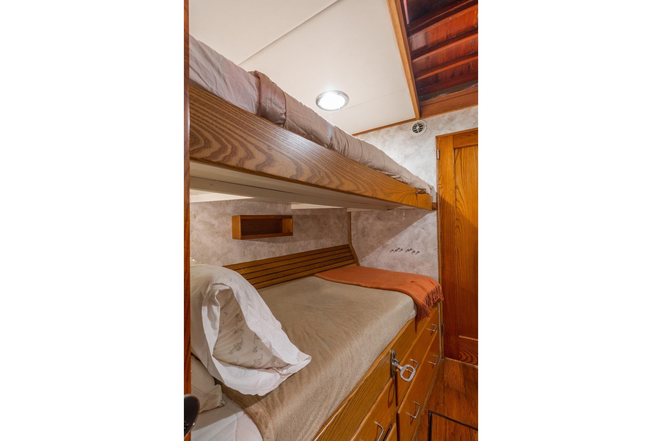 Cozy 1963 Trumpy Classic yacht cabin with wooden bunk beds and warm lighting.
