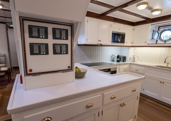 Modern yacht kitchen with white cabinetry, control panels, and porthole window, Custom 52m, 2014.