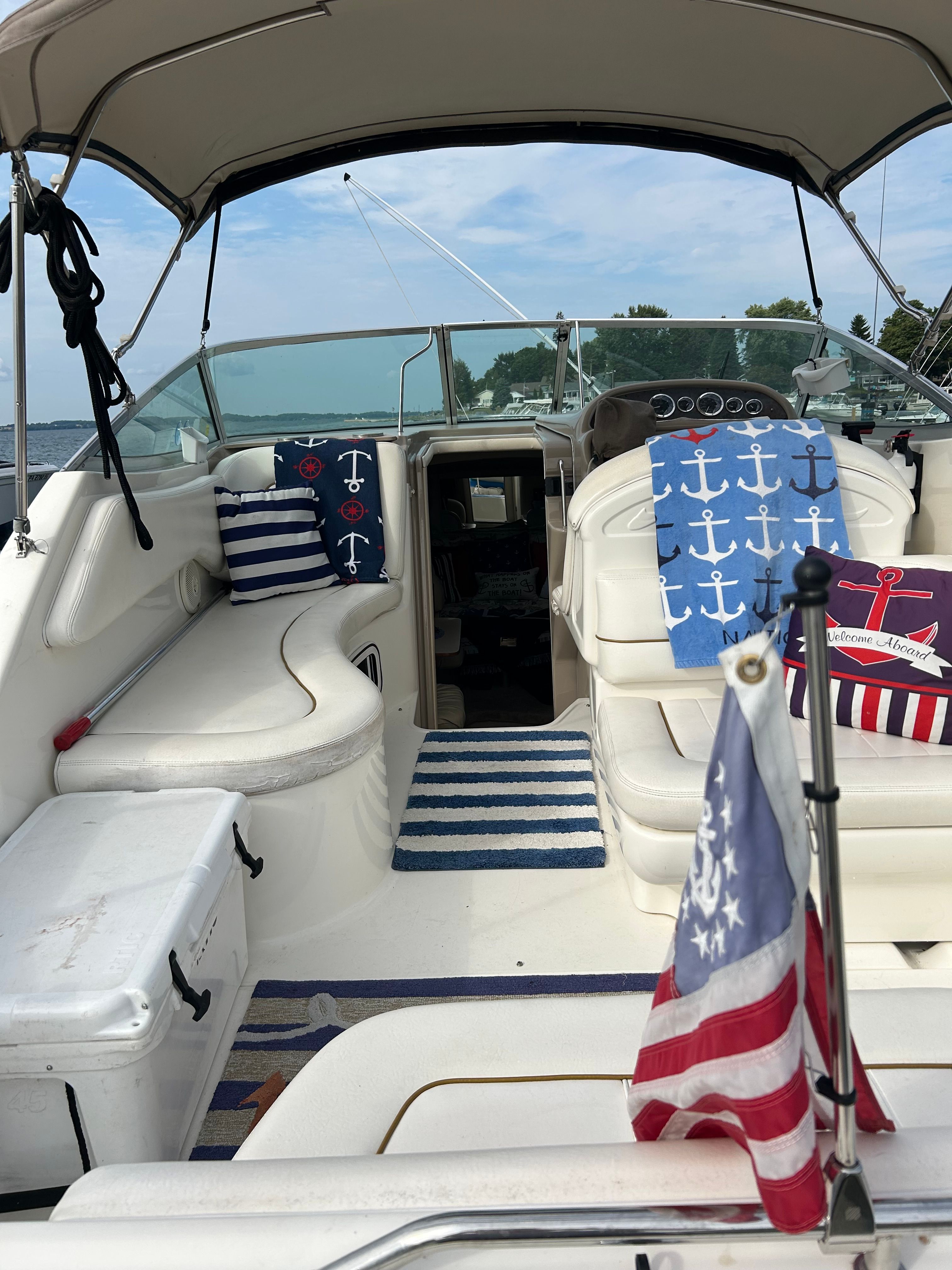 The image shows the cockpit of a 1999 Sea Ray 270 Sundancer Special Edition. It features nautical-themed cushions and an American flag motif.