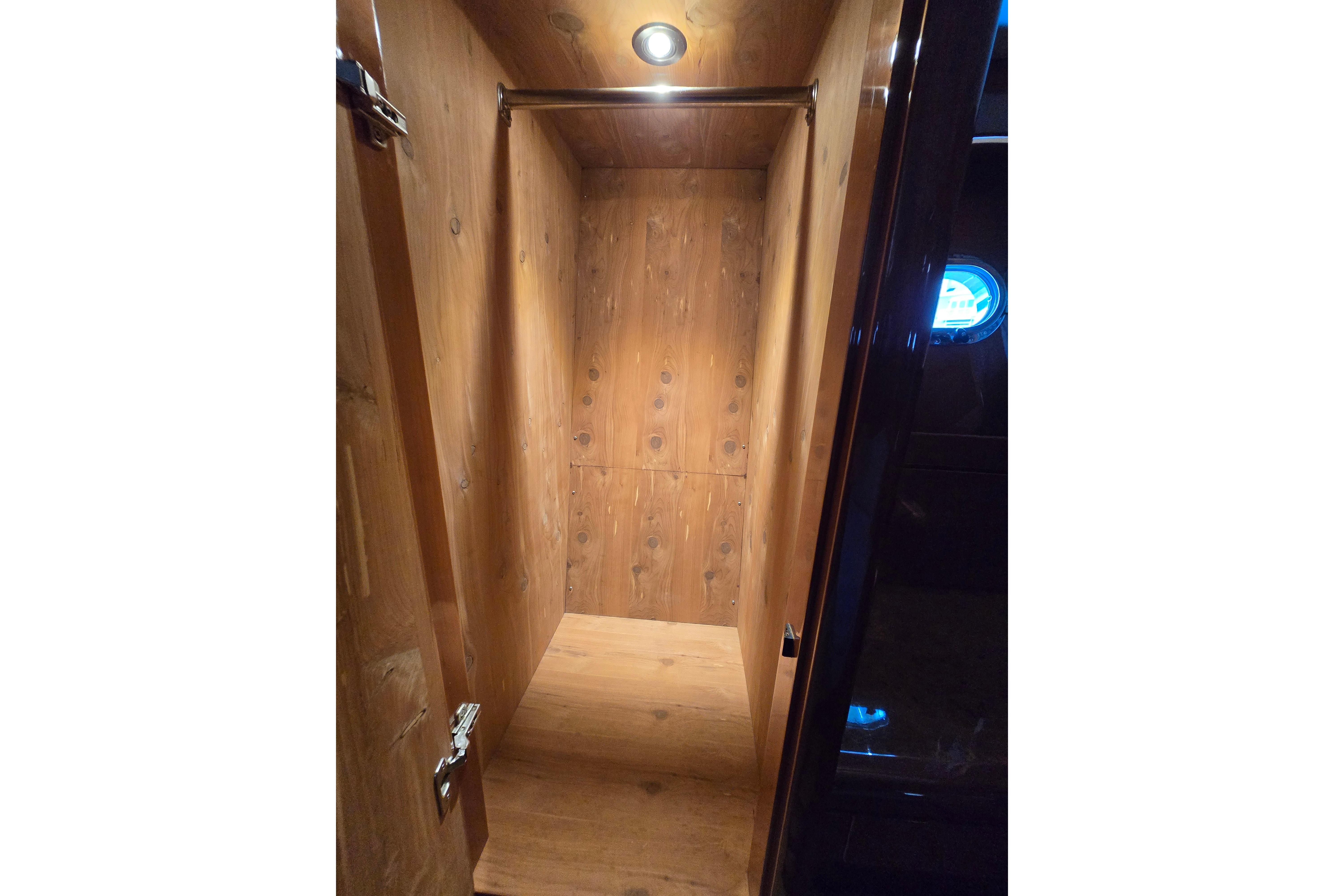 Wooden interior closet on 2004 Grand Harbour 58 yacht, featuring a hanging rod and spotlight.