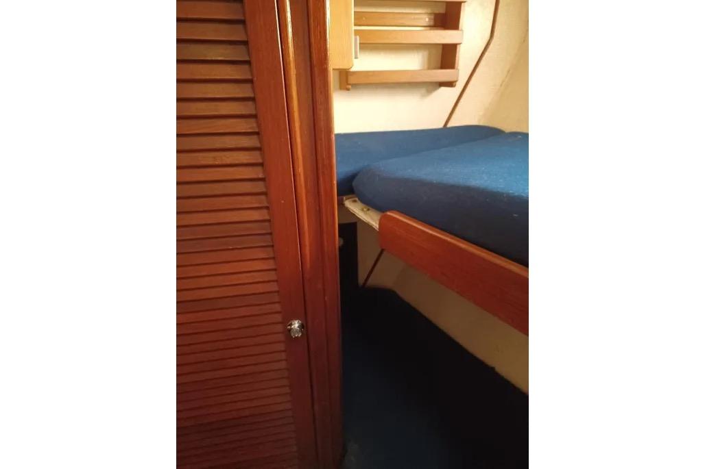 Interior cabin of 1977 Morgan Out Island 51 sailboat with wooden door and blue bedding.