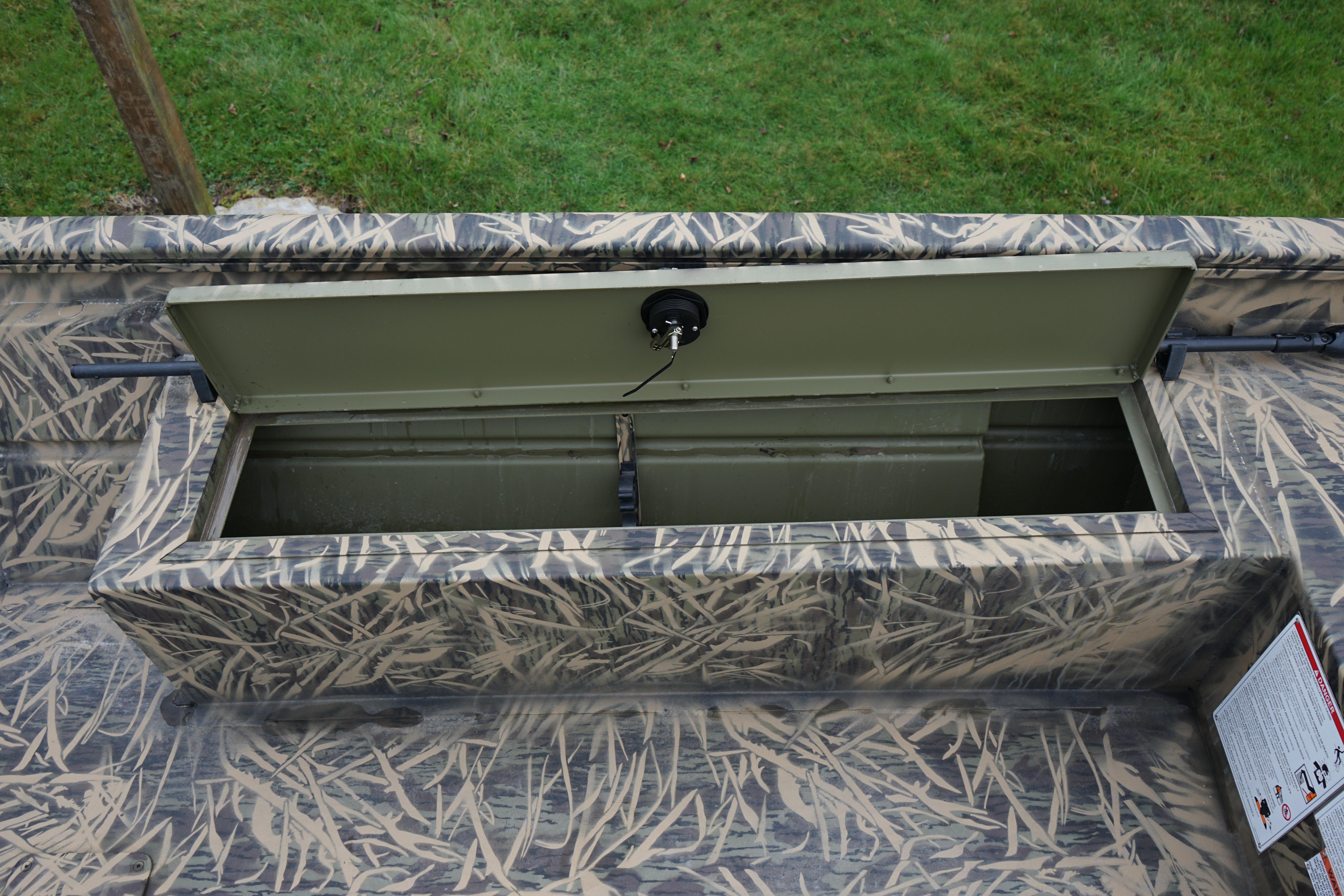 2024 Lund 1760 Predator Tiller boat storage compartment with camouflage design.