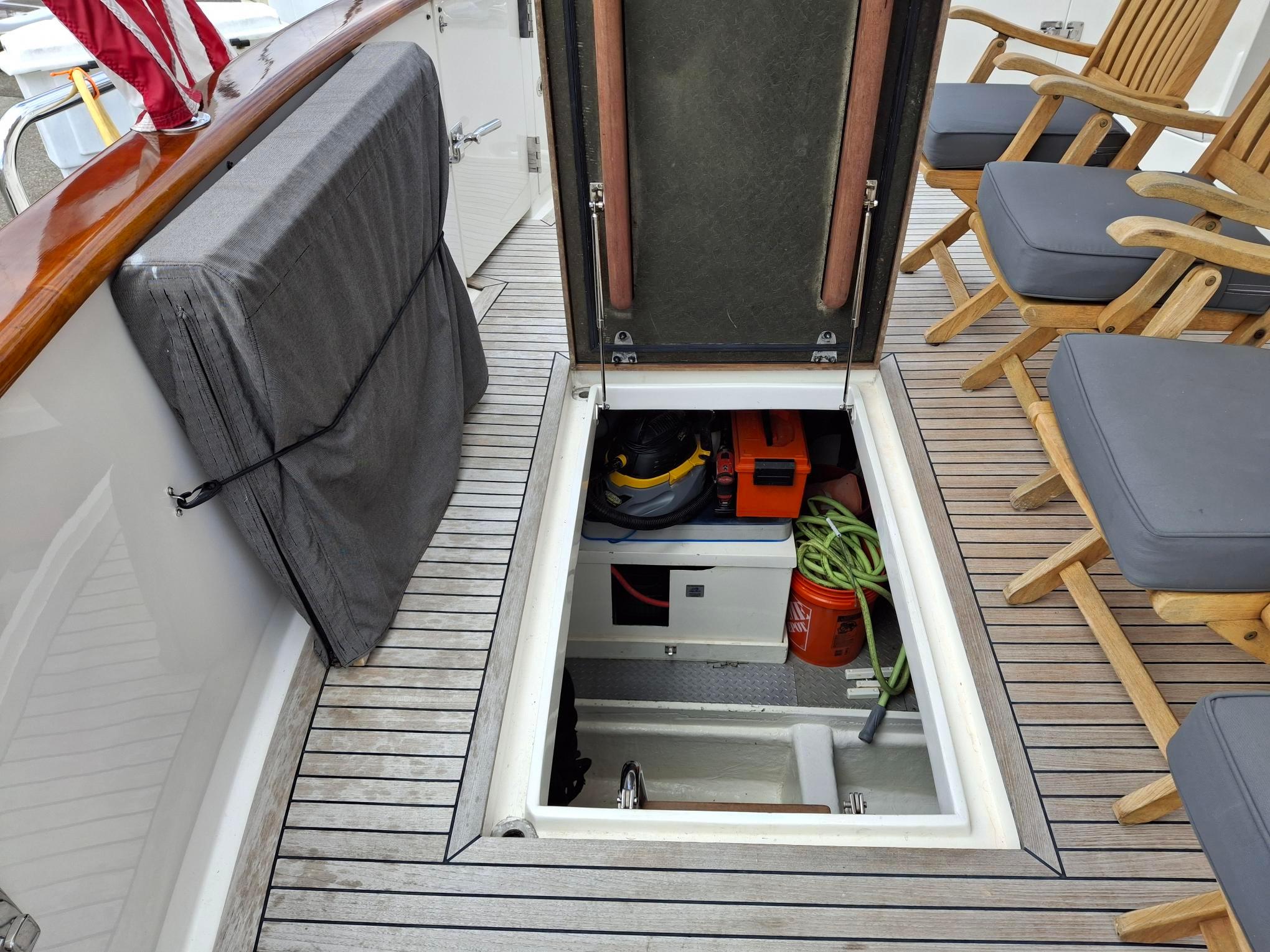 Open hatch on 2004 Ocean Alexander 64 Pilothouse, revealing storage with equipment and chairs on deck.