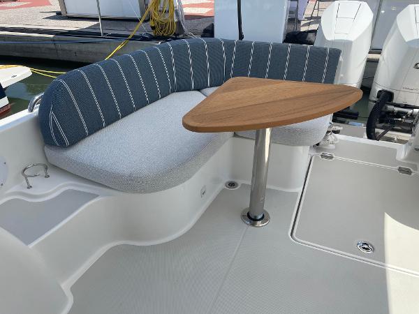 Back Cove 34O 2024 boat seating area with striped cushions and a wooden table.