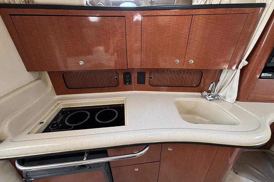 2002 Sea Ray Sundancer 320 galley with stove, sink, and wooden cabinetry.