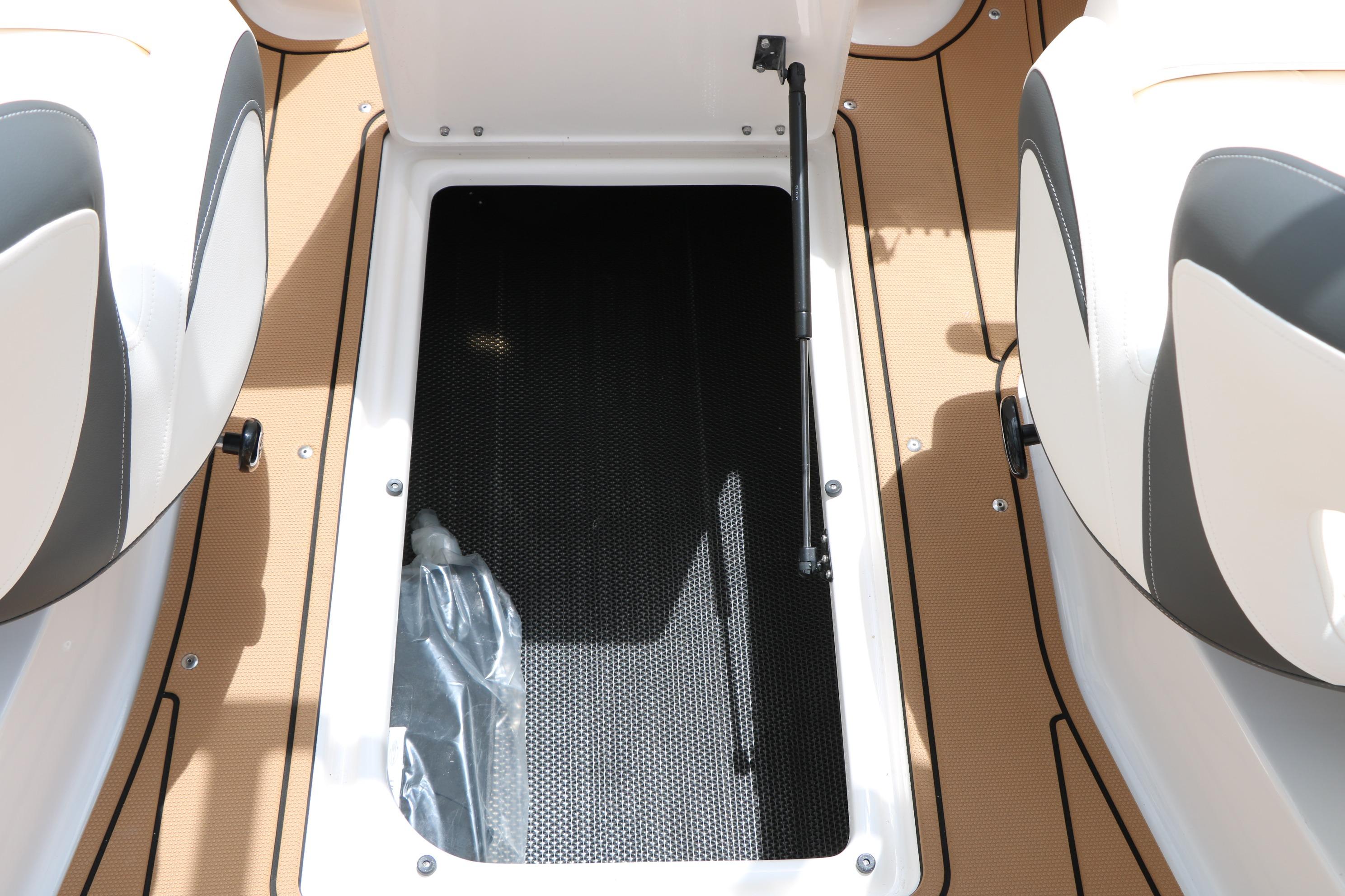 2025 Chaparral 23 SSi boat storage compartment with open hatch and cushioned seating.