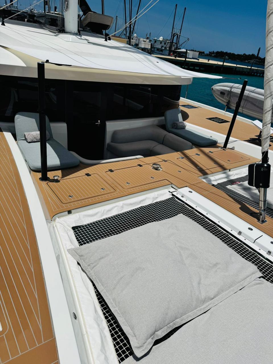 2024 Lagoon 65 yacht deck with cushioned seating and netting, docked in a marina.