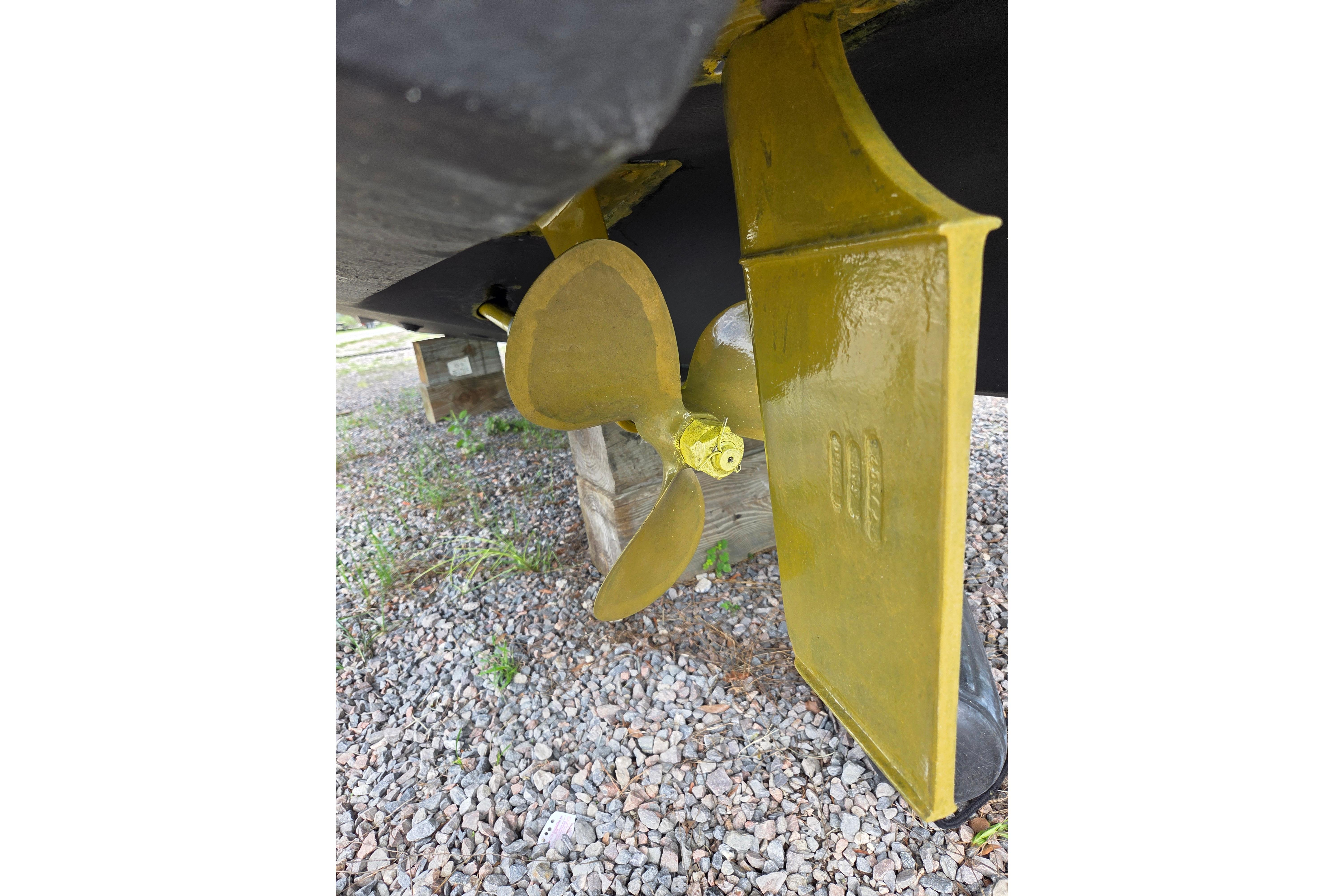 Propeller and rudder of a 2000 Sea Ray 340 Sundancer on gravel surface.