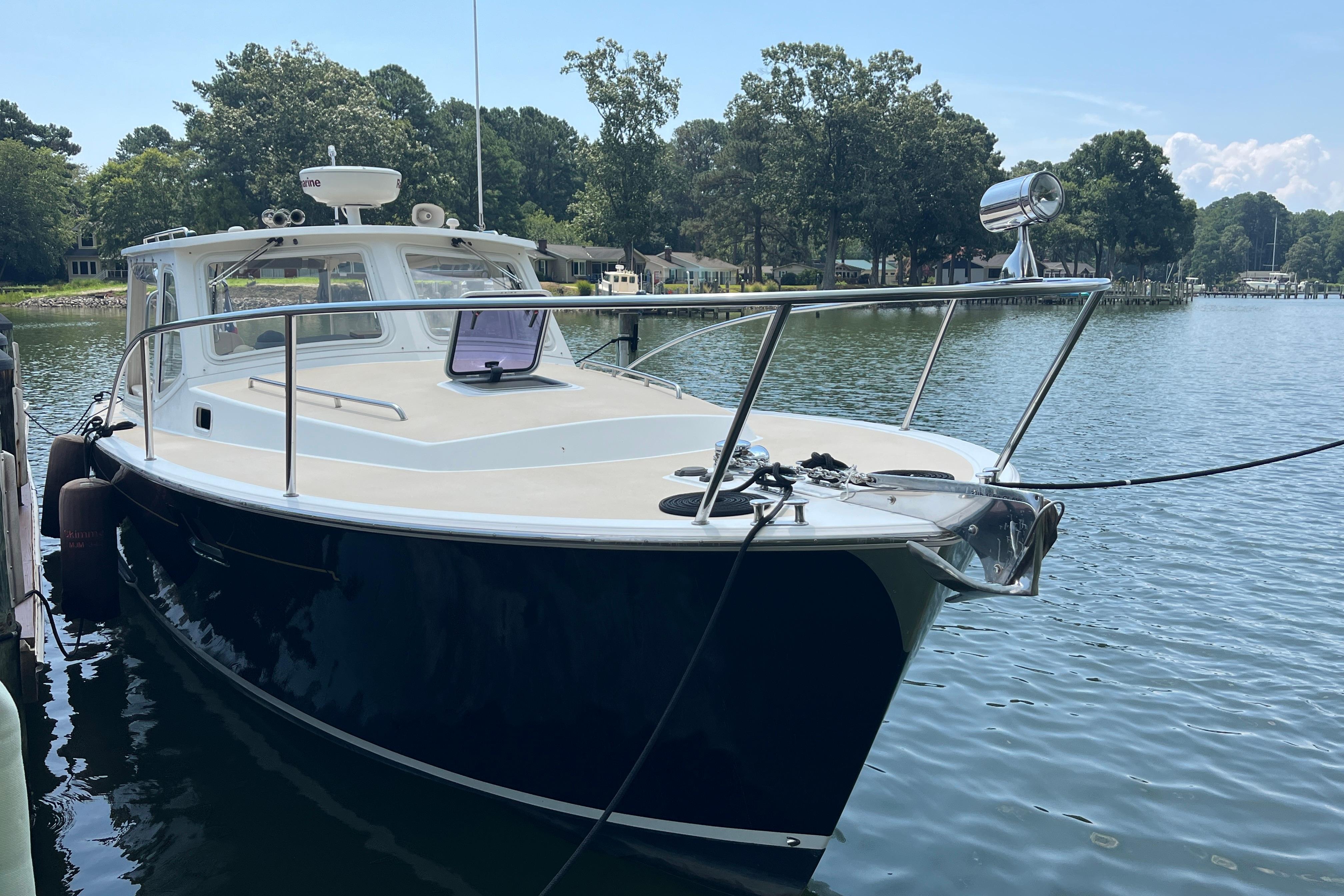 2006 MJM 34z boat docked on a serene lake with lush greenery.