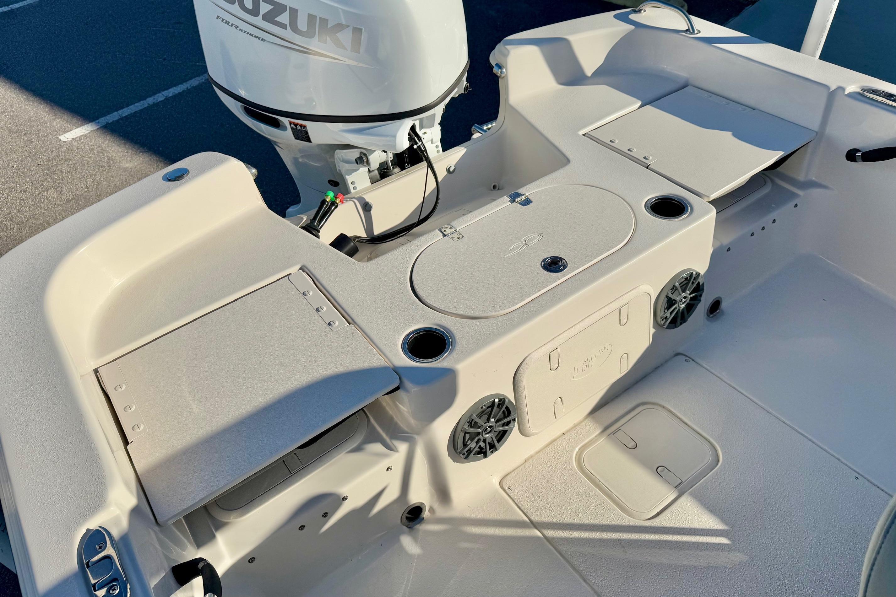 2025 Carolina Skiff 21 LS boat interior with Suzuki engine, featuring storage compartments and cup holders.