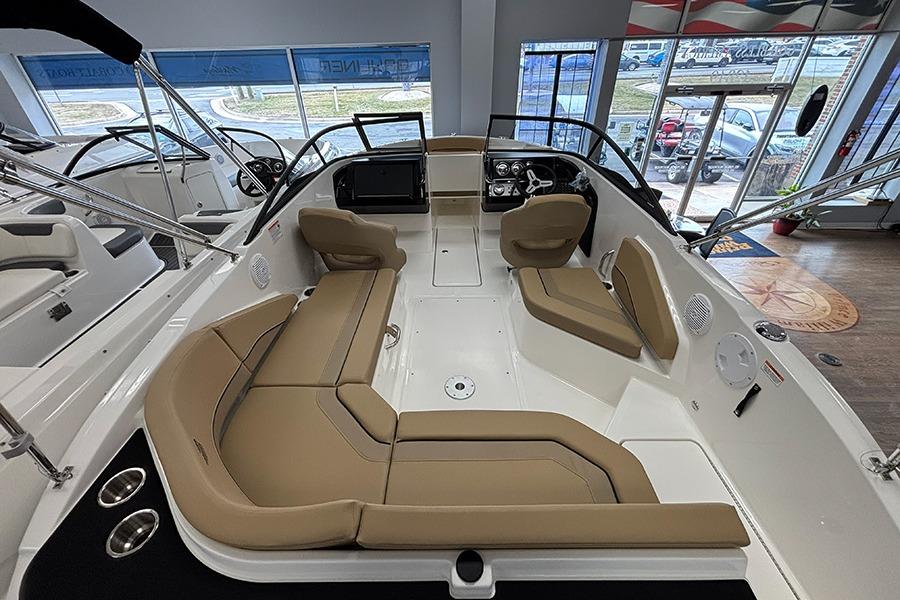 2026 Bayliner V20 boat interior with tan seating and modern dashboard in showroom.