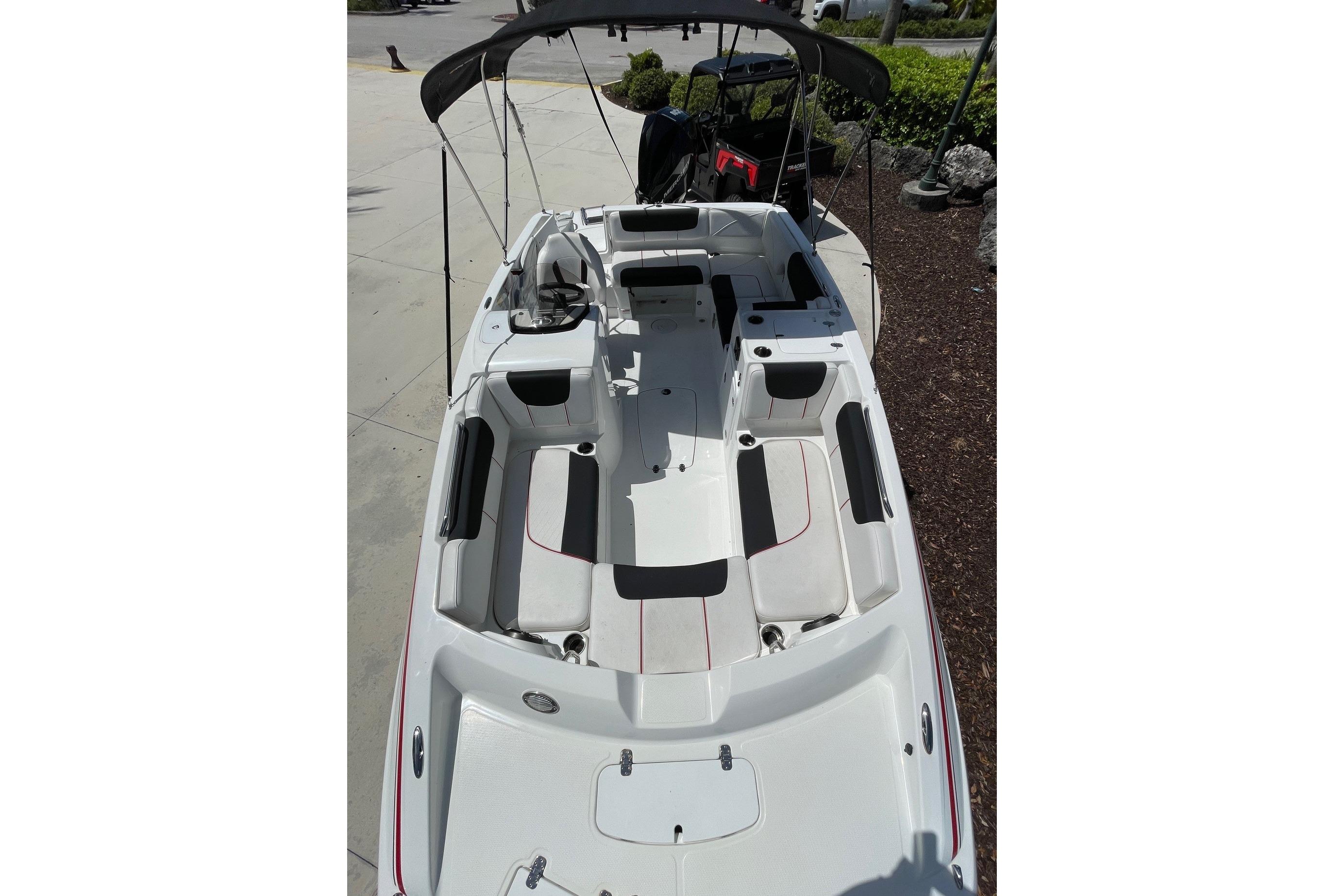 2024 Tahoe 2150 OB boat with spacious seating and canopy, docked outdoors.