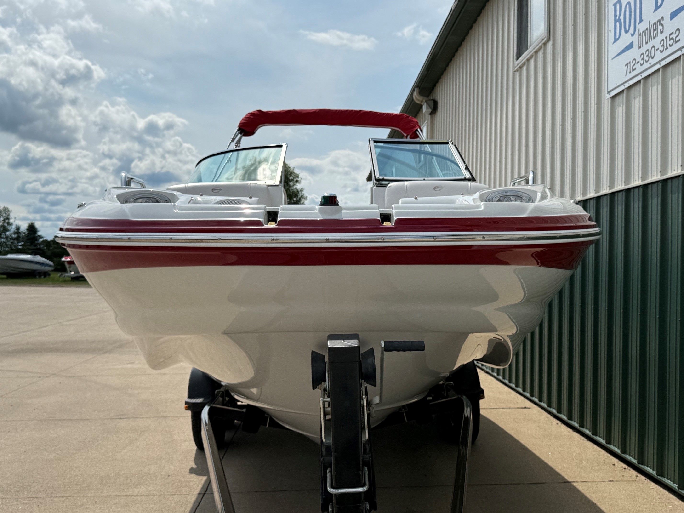 A 2012 Crownline 252 EX boat on a trailer in front of a building.