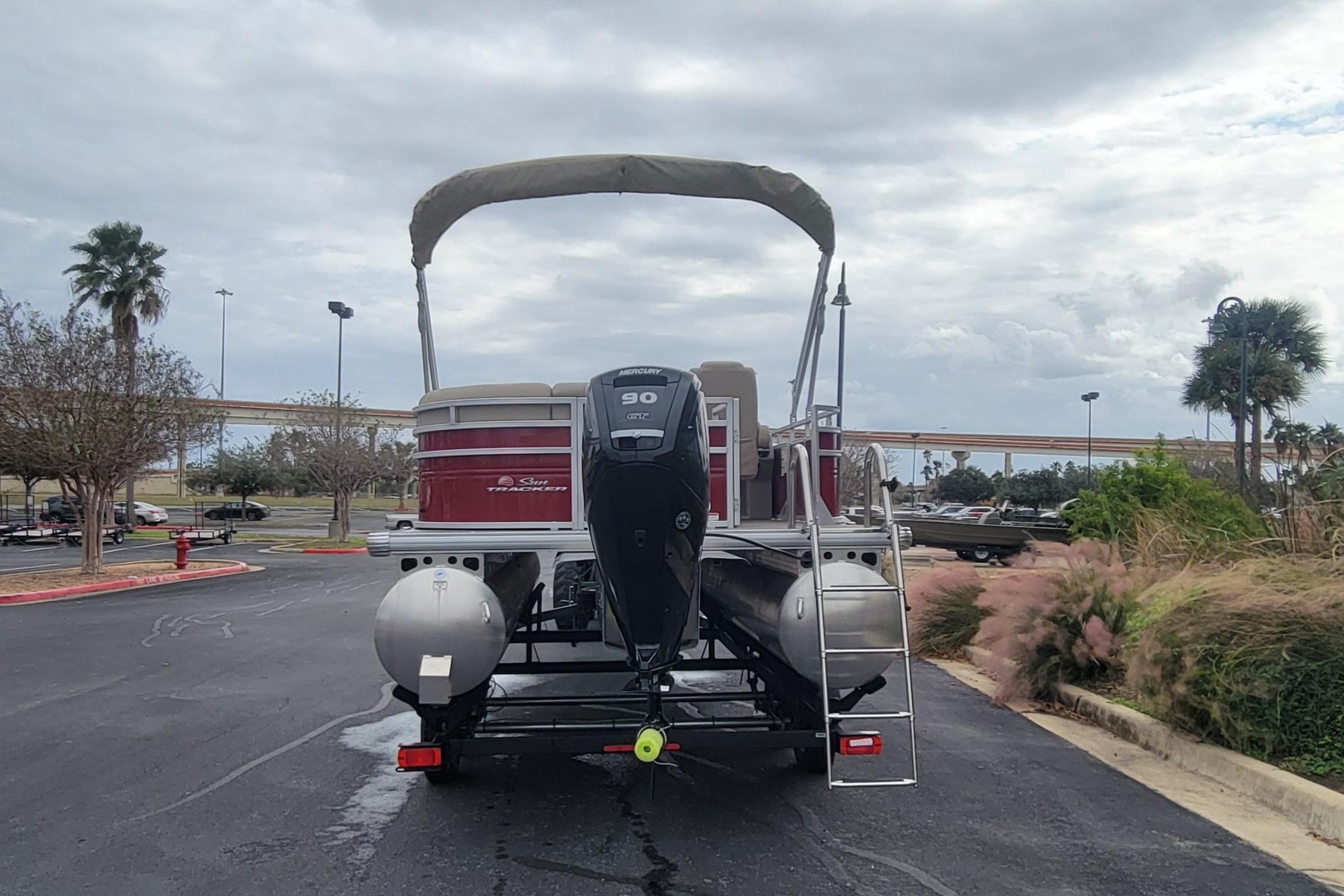 2025 Sun Tracker Party Barge 20 DLX pontoon boat with Mercury 90 engine, parked outdoors.