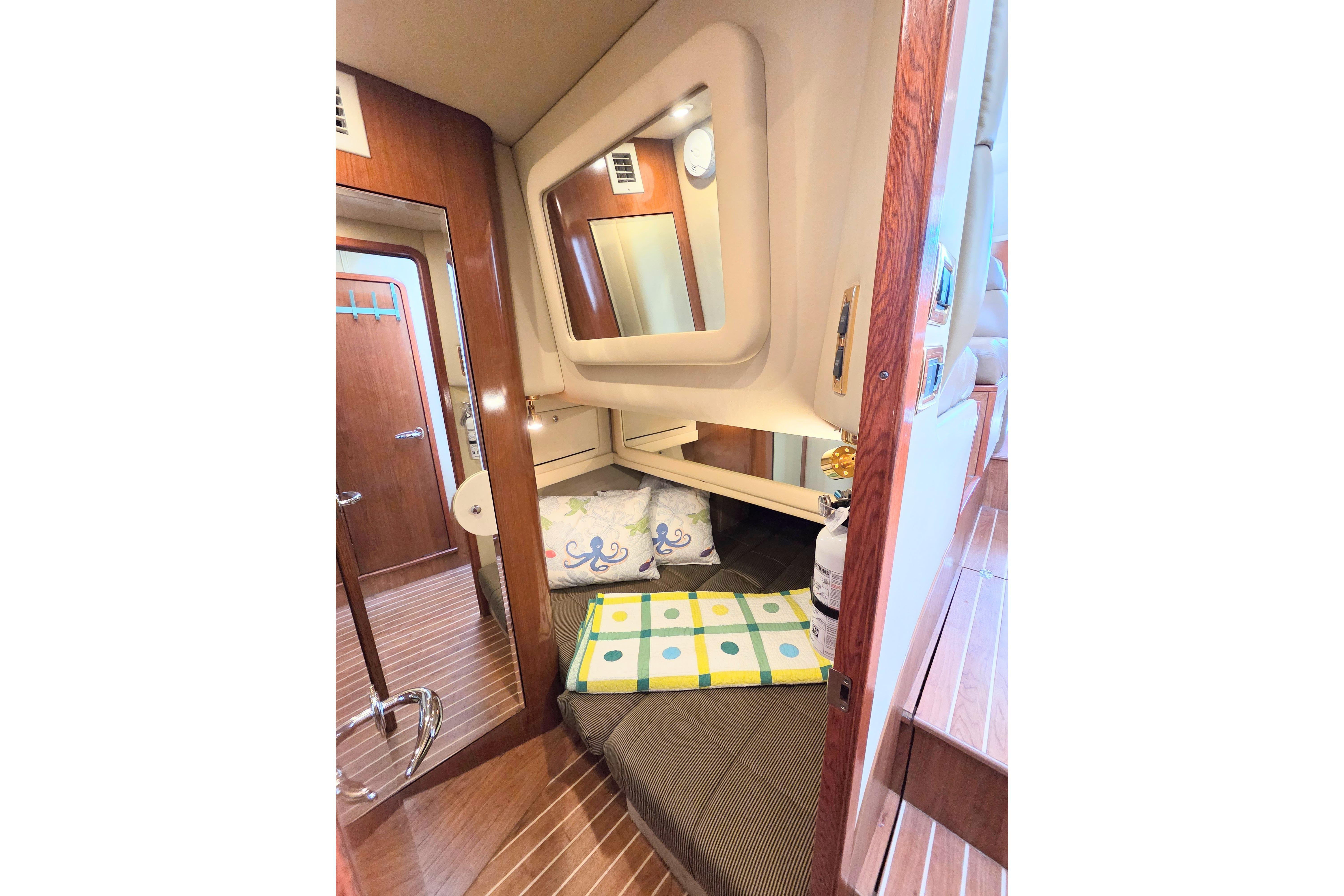 Interior cabin of 2002 Sea Ray 480 Motor Yacht with cozy bedding and wooden accents.