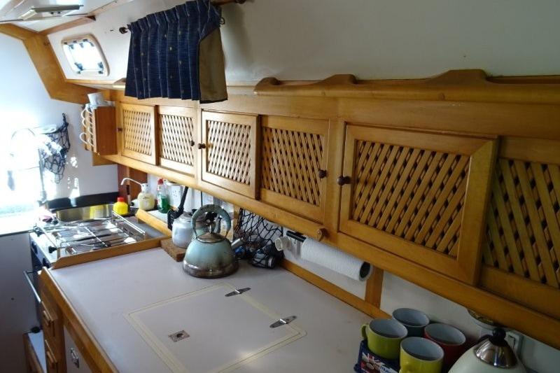 Galley kitchen of 1991 Ocean Bound Yachts Crossbow 40 with wooden cabinets and stove.