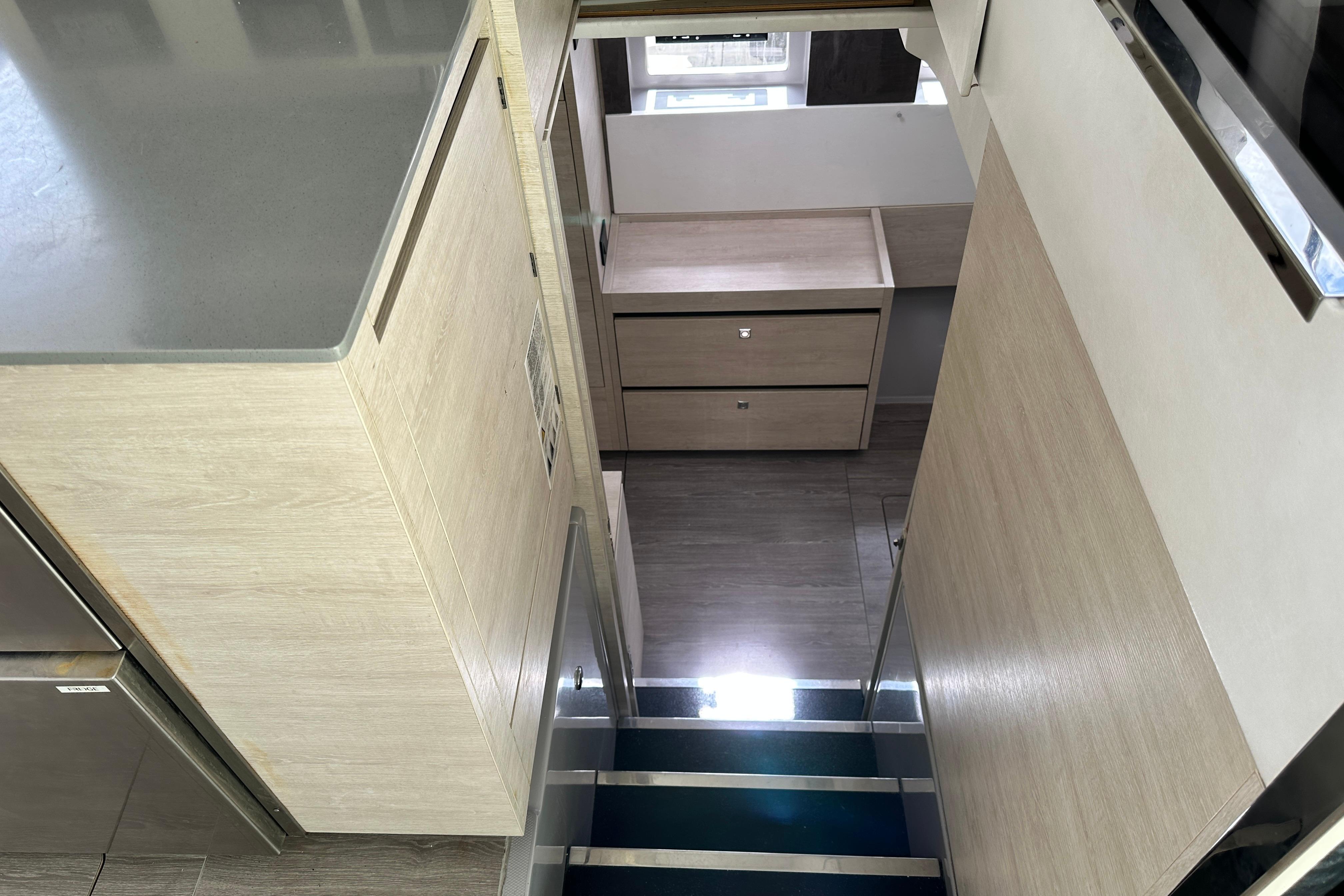 Modern interior of 2021 Leopard 50 yacht, featuring sleek wooden cabinetry and stairs.