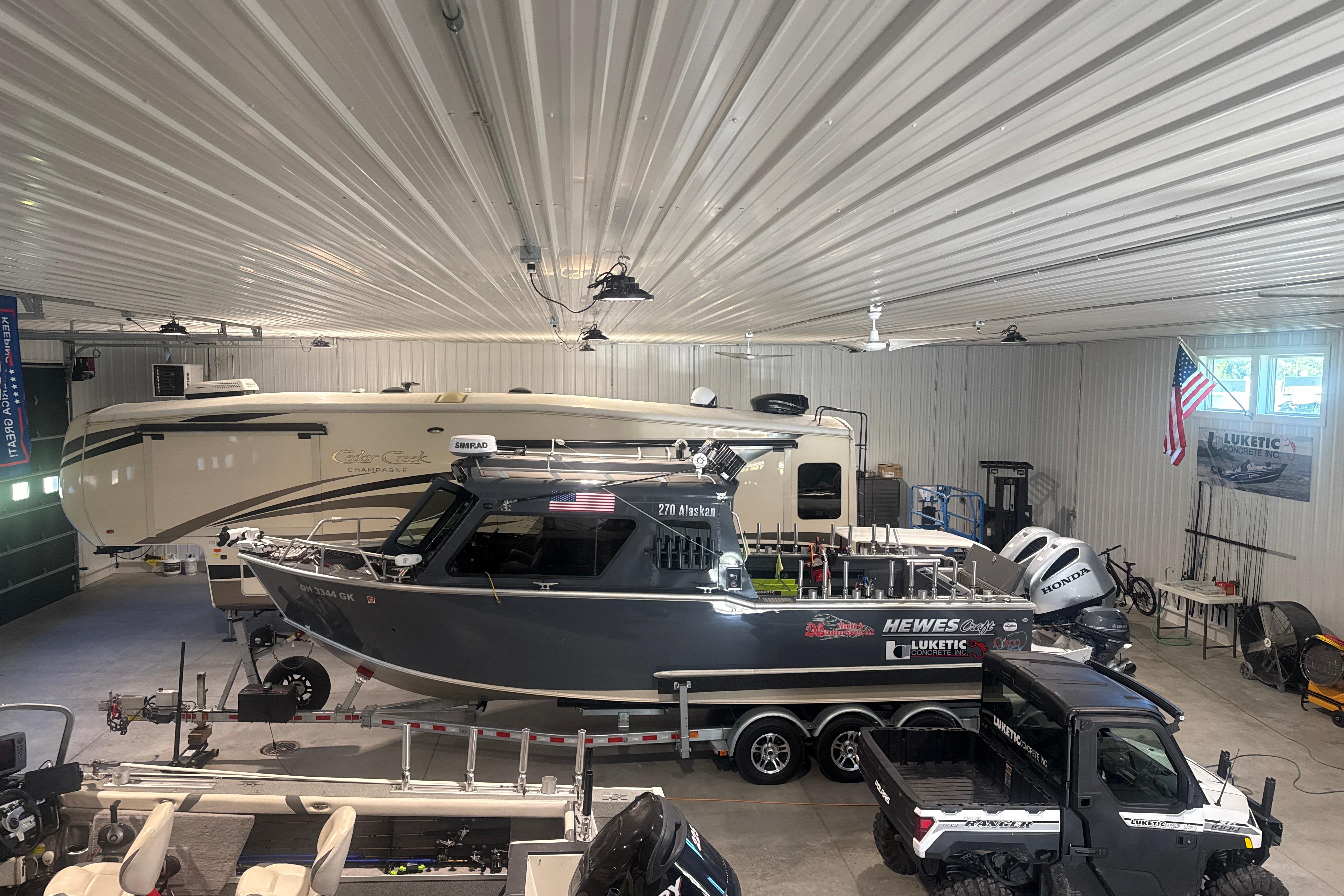 2022 Hewescraft 270 Alaskan Hardtop boat in a spacious garage with vehicles.
