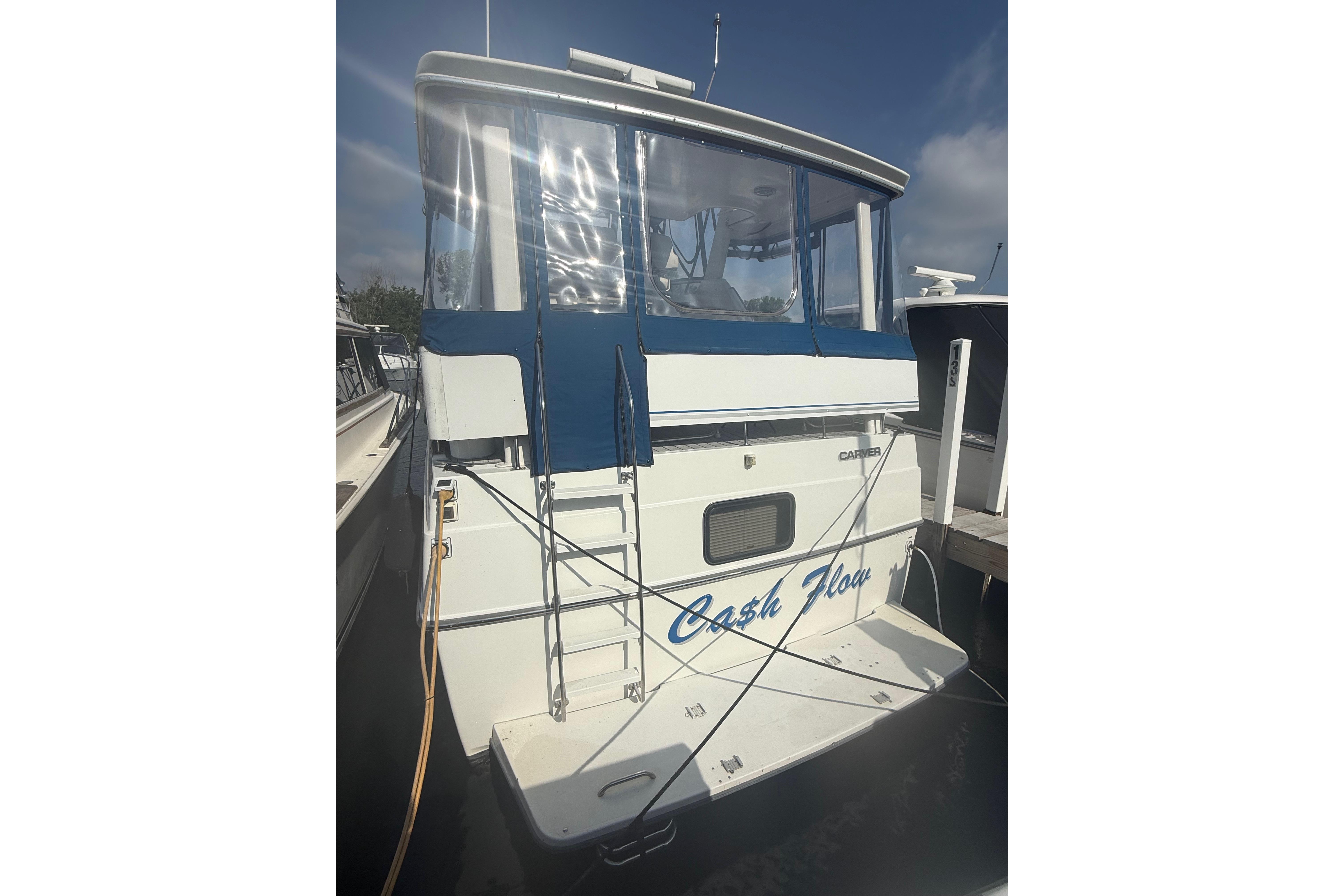 1992 Carver 33 Aft Cabin Motor Yacht docked, featuring blue canopy and ladder.
