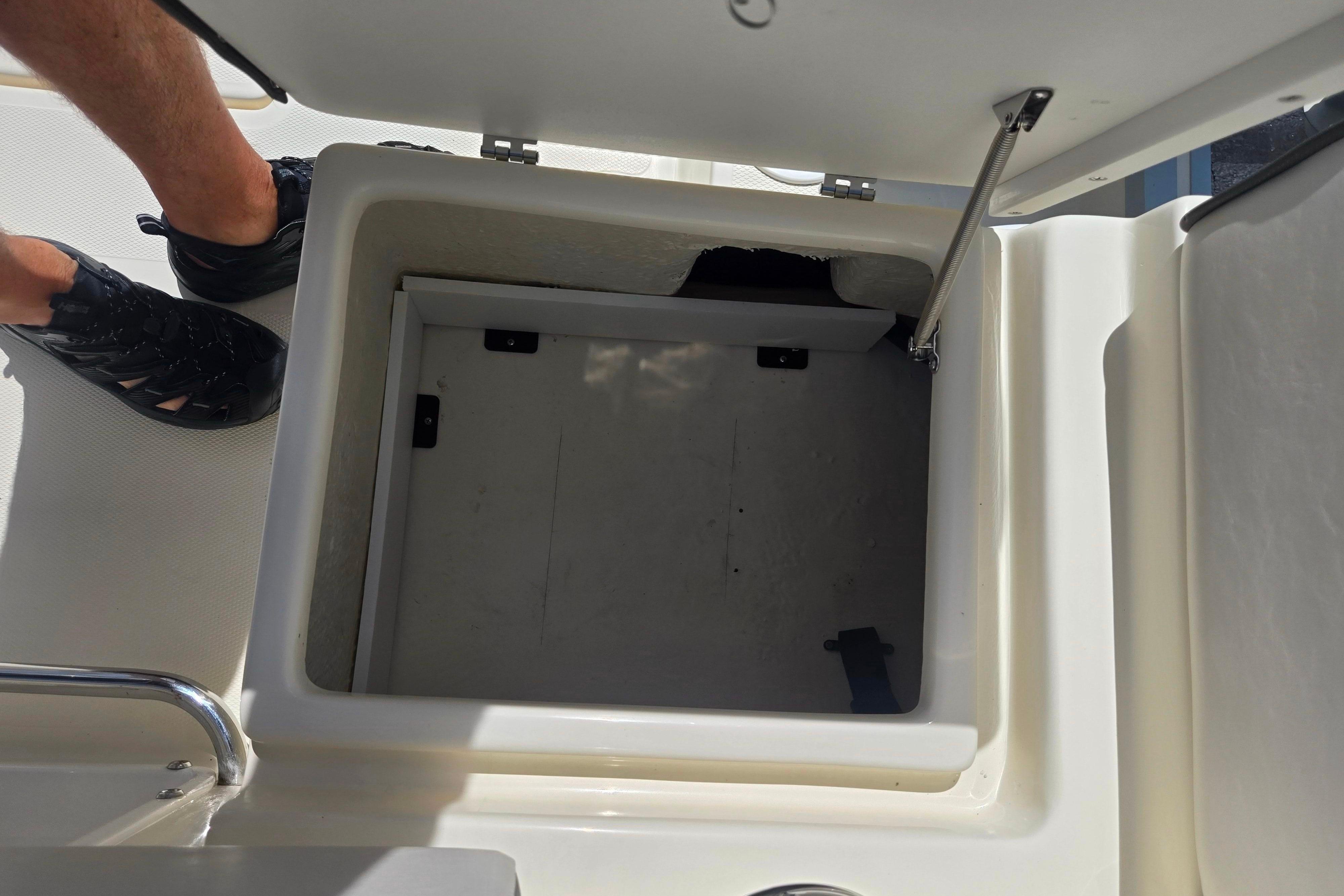 Open storage compartment on a 2016 Key Largo 2000CC boat, with visible footwear.