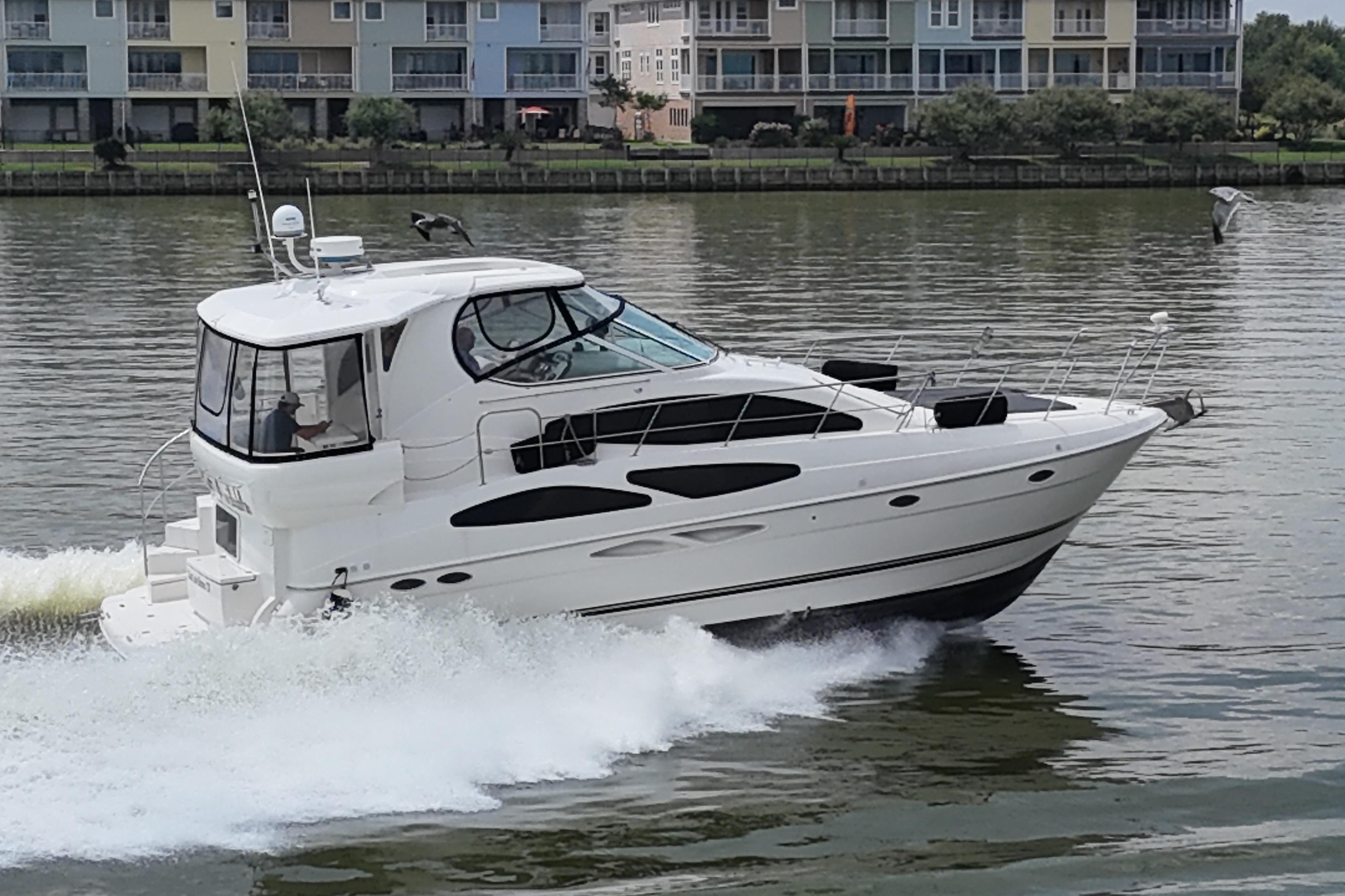 2004 Cruisers Yachts 405 Express Motoryacht cruising on a calm river near waterfront buildings.